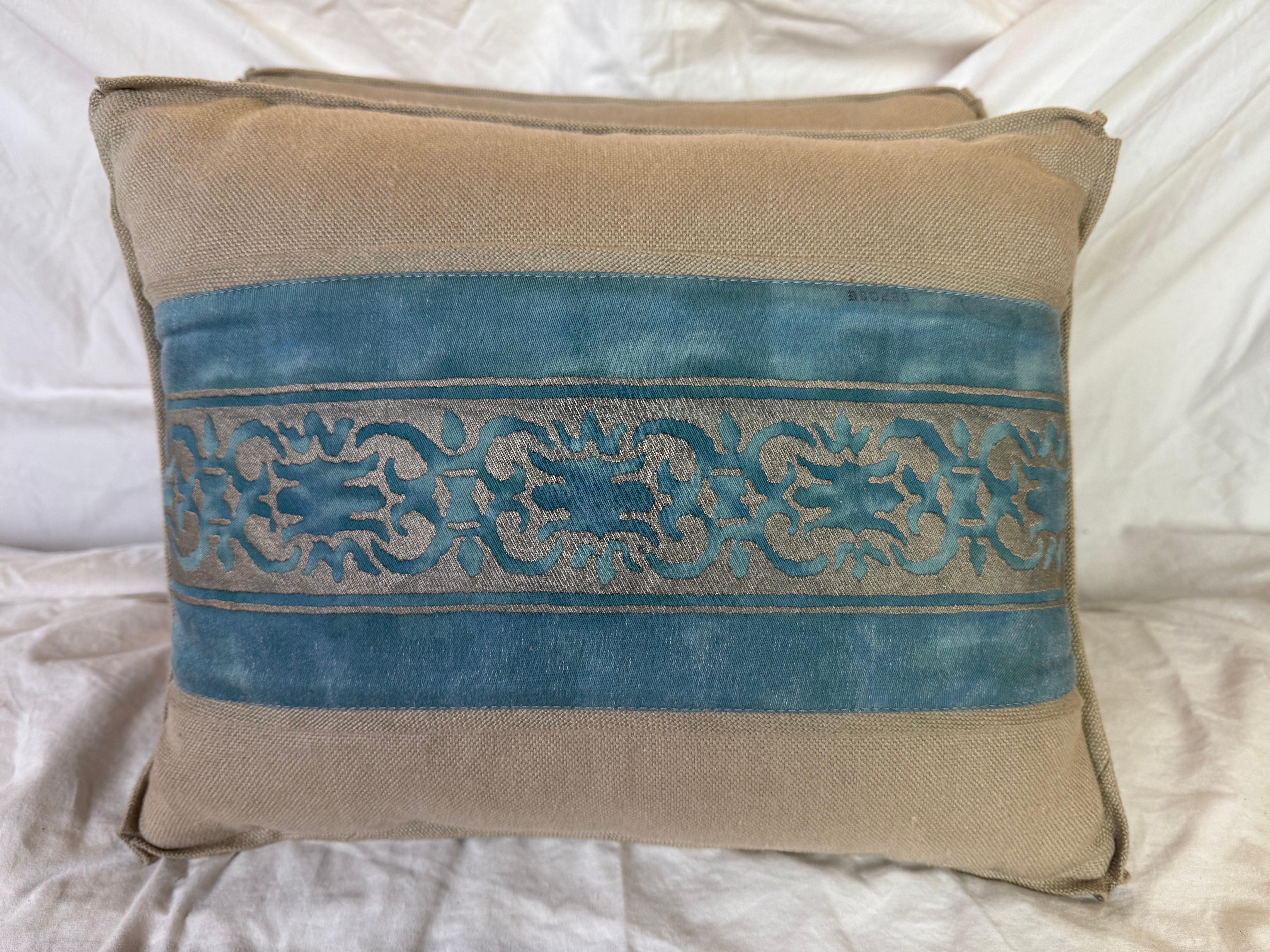 These pillows feature a sophisticated combination of natural linen and Fortuny cotton. The base fabric is a neutral, beige-toned linen with a subtle woven texture.

A striking horizontal band of blue-green cotton runs across the center, adorned with