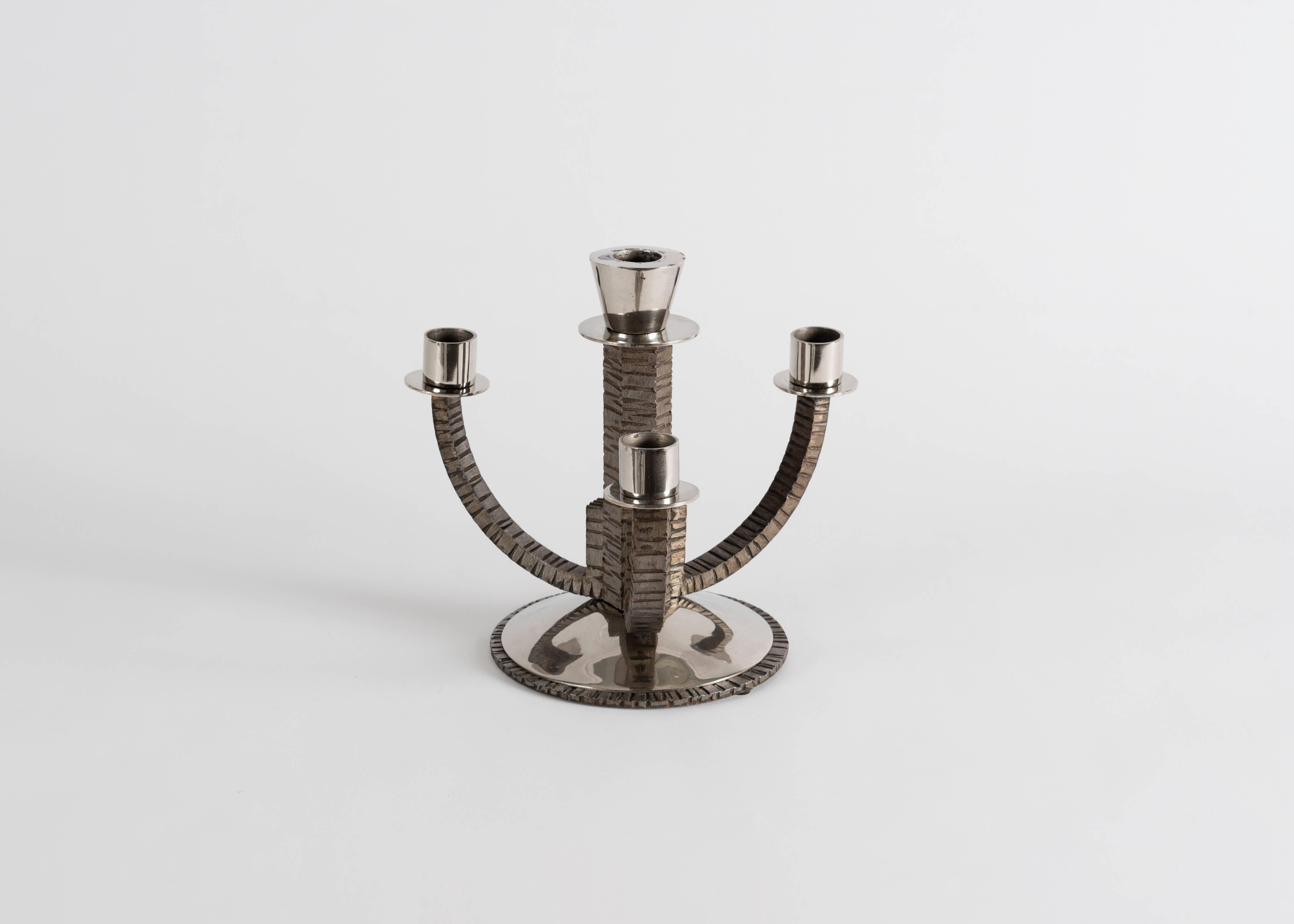 This elegant pair of candlesticks, in a remarkably textured hand-worked steel, have four arms apiece: three curved, and one central--straight, and taller than the others.