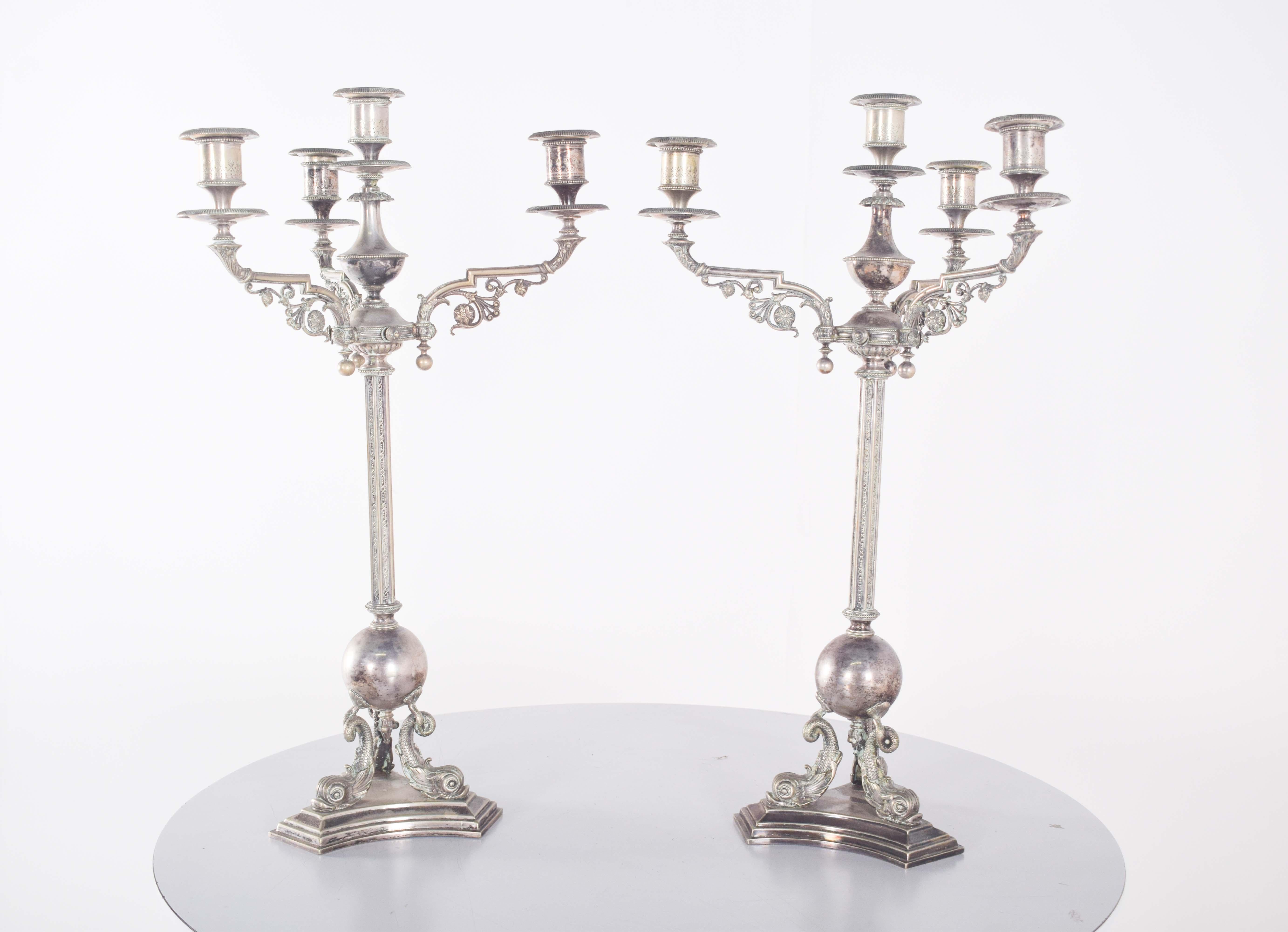 Coppia di candelabri a quattro luci, in conchiglia. Con una struttura alta e imponente, con tre bracci curvi e uno dritto, sono decorati nei dettagli, ognuno dei quali sostiene un portacandele. La disposizione simmetrica dei bracci crea un