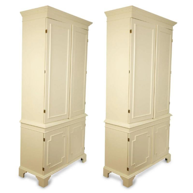 A pair of custom, cream lacquer four door armoires with molding on each door to create a raised panel motif, square on the top two doors and notched squares on the lower doors, and traditional style molding on top and feet at base.