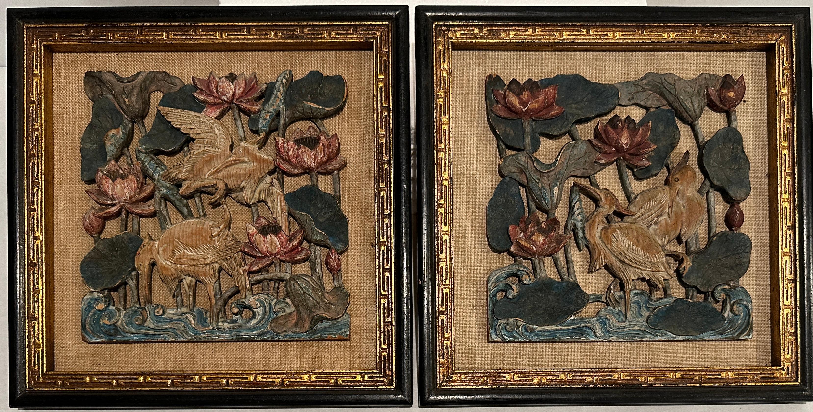 Paire de panneaux sculptés et peints en haut-relief, joliment sculptés et encadrés. Couleurs subtiles avec une finition usée appropriée à l'âge, représentant des grues (oiseaux) parmi des fleurs debout dans l'eau avec des vagues ondulantes.