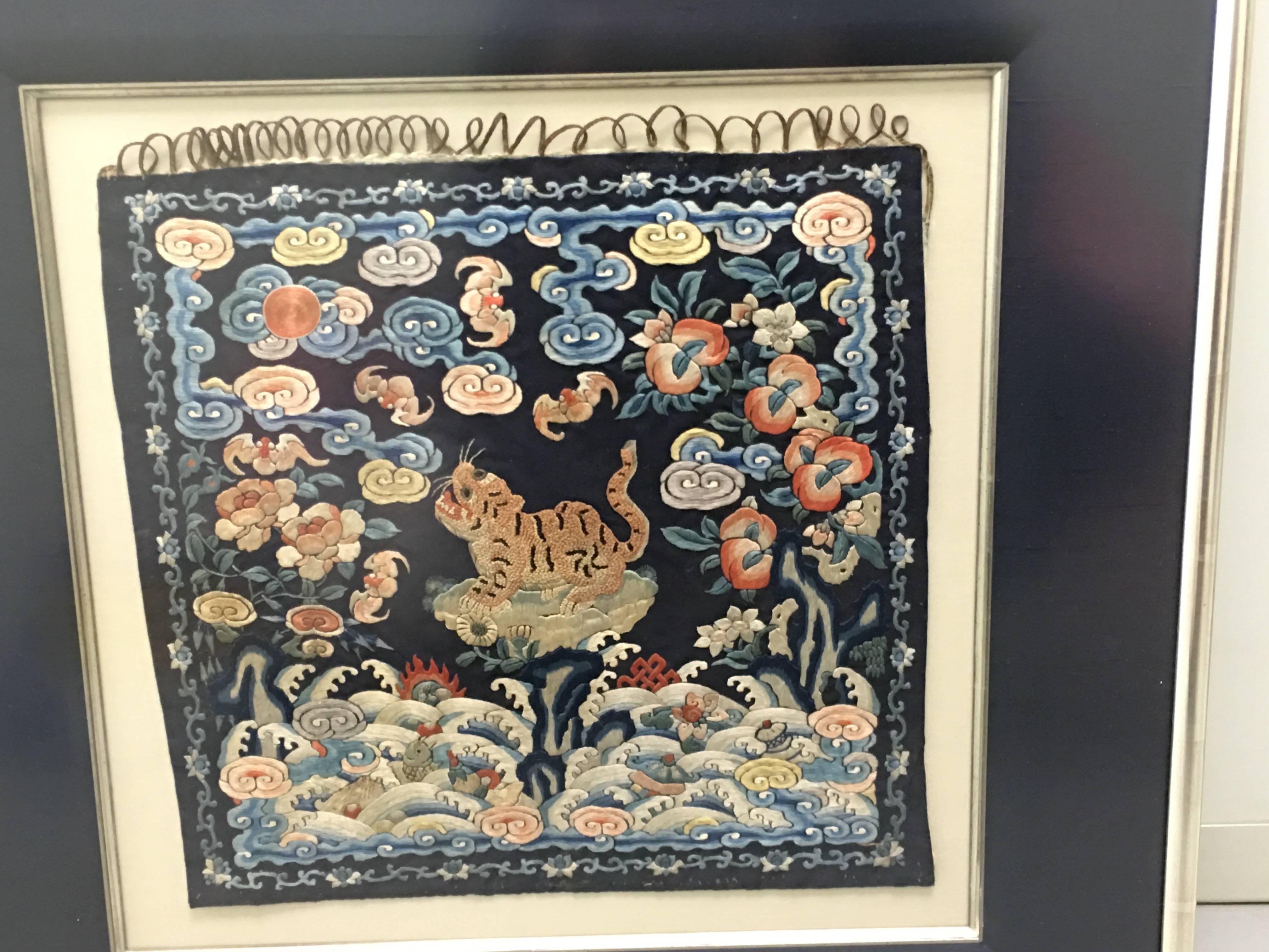 Pair of 19th century framed Chinese military rank badges. Each badge features a central tiger motif, indicating 4th rank. Midnight blue silk backing with multi-color embroidered detailing and gold couched stitching. Mounted on ivory silk with
