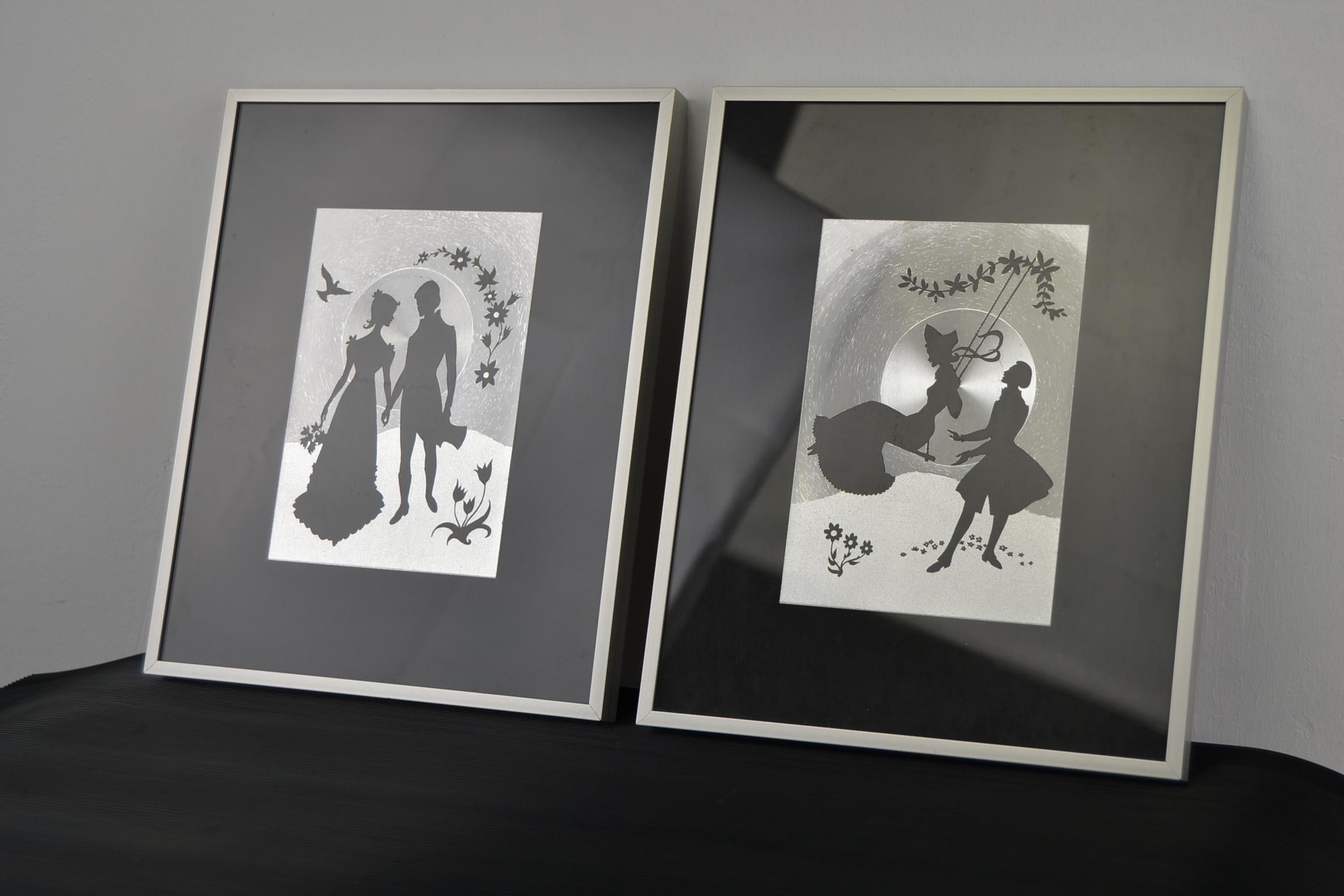 Pair of aluminium framed metallic art prints with Romantic couple.
This two lovely vintage wall decorations have a romantic scene with a man and a women. One work they are walking hand in hand and are flirting,
on the second one he's pushing her