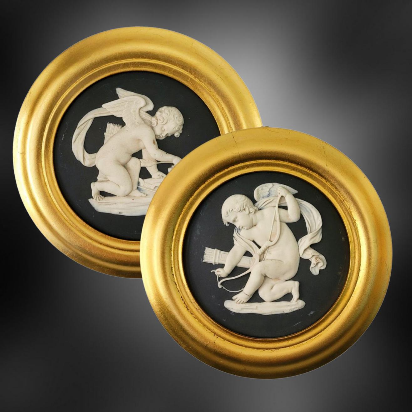 An exceptionally fine pair of roundels in black jasperware, decorated with two images of Cupid: The first sharpening his arrows; the second, of him stringing his bow.

Cupid is a popular figure from ancient Roman mythology who is commonly depicted