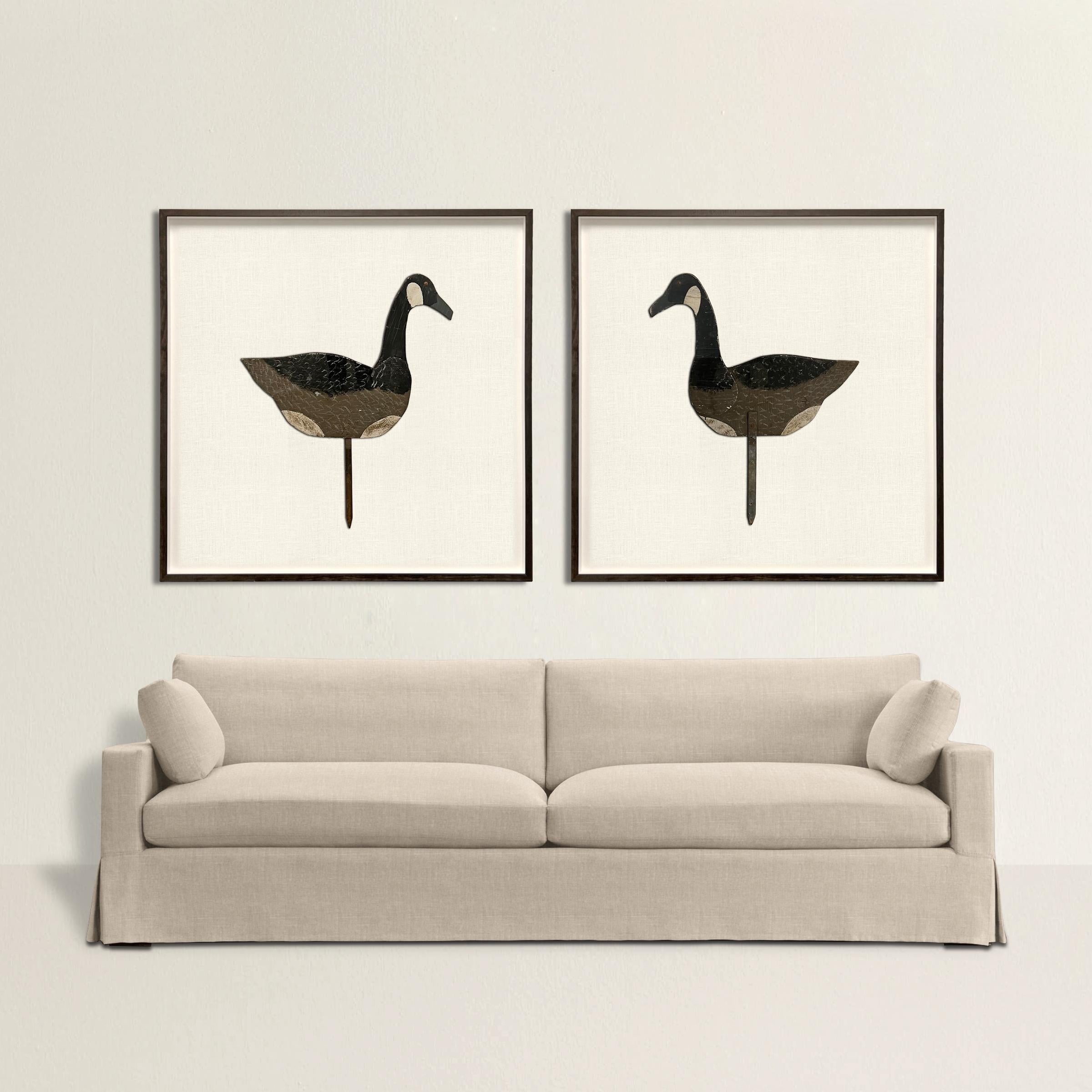 A whimsical and striking pair of vintage American wooden Canada goose decoys of impressive scale, mounted on white linen, and framed with driftwood-grey stained maple frames. The perfect decoration in your country home or cabin!