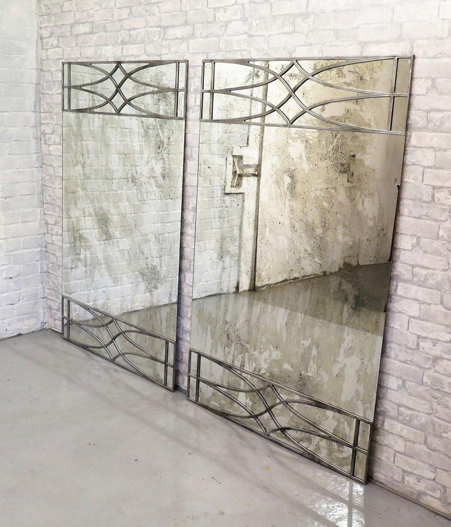 Sheraton Revival mirrors originate from England from the 20th century. 
Both are frame-less to give a contemporary twist with upper and lower silver panel motifs, made with real silvered distressed glass, formidable when paired together.
Portrait or
