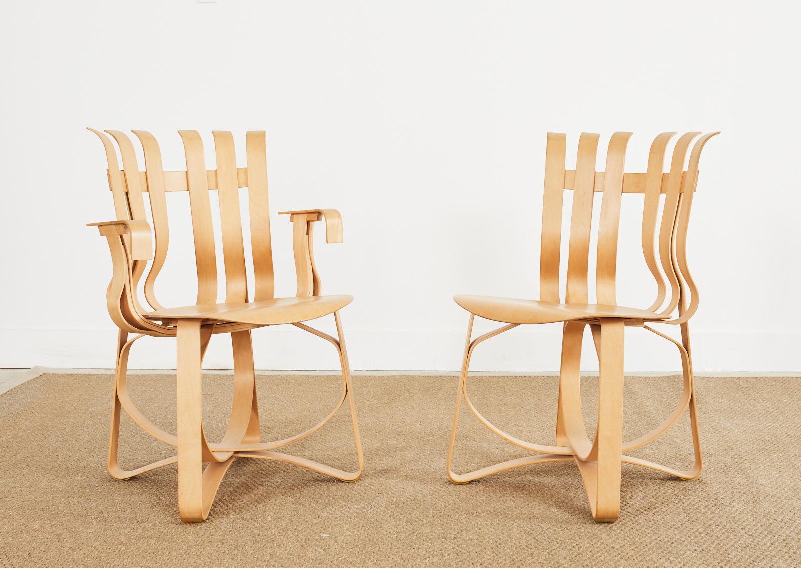 Iconic pair of maple plywood hat trick chairs designed by Frank Gehry for Knoll. Each beautiful chair is signed and dated on bottom. Constructed on 8-7-1993 and 8-`4-1993. The set consists of one armchair and one dining chair. The later measuring 19