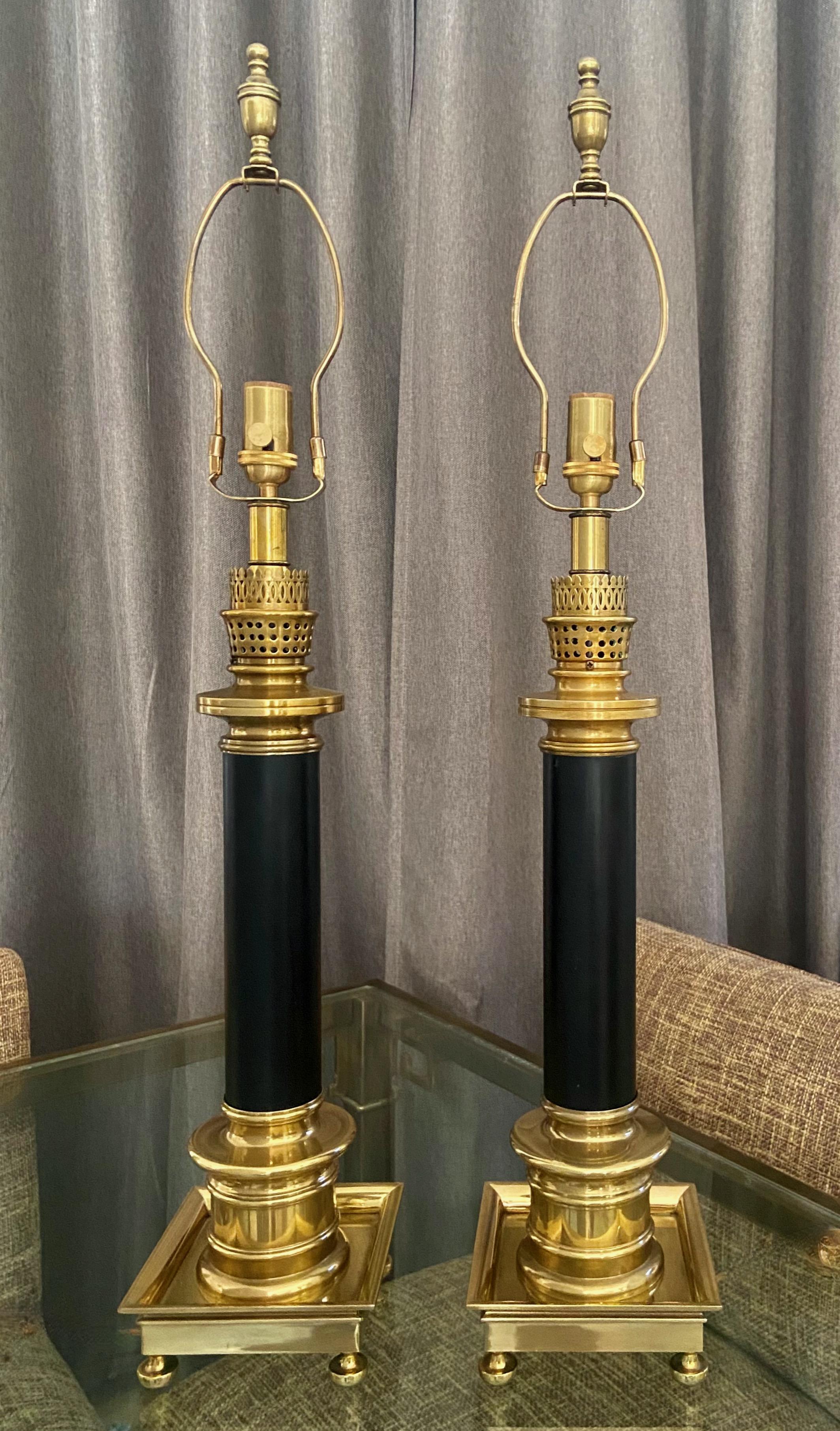 Pair of large solid brass and black painted column table lamps by Frederick Copper for Fitz & Floyd. New three-way brass sockets. Includes original harps and finials. (Frederick Copper label appeared on replaced sockets.) 
Measures: Height to top