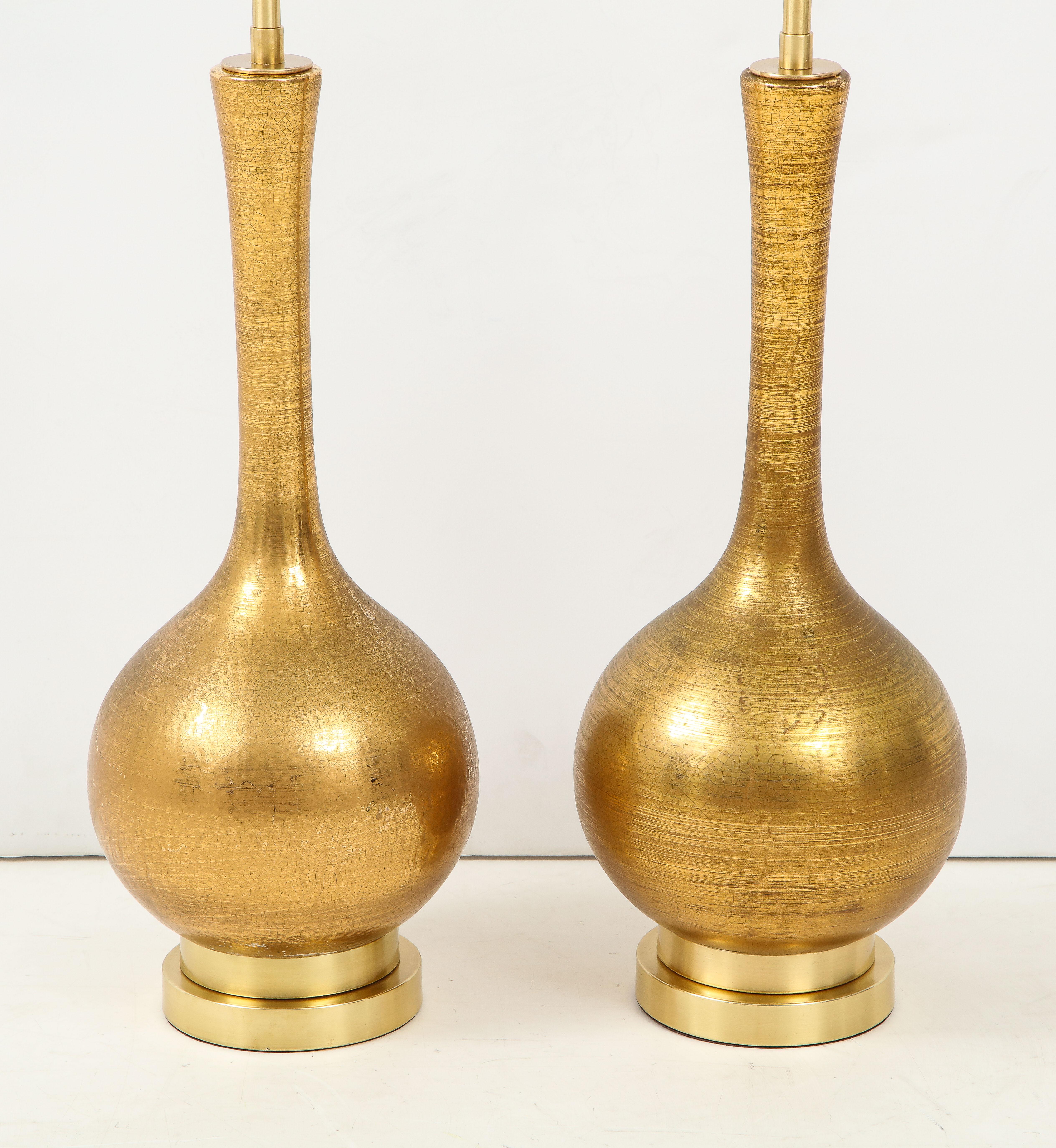 Pair of gold ceramic lamps with a beautiful crackle glazed finish.
The lamps are mounted on double stacked brass bases and they have been newly rewired with polished brass double clusters.
There are a couple of minor glaze imperfections consistent