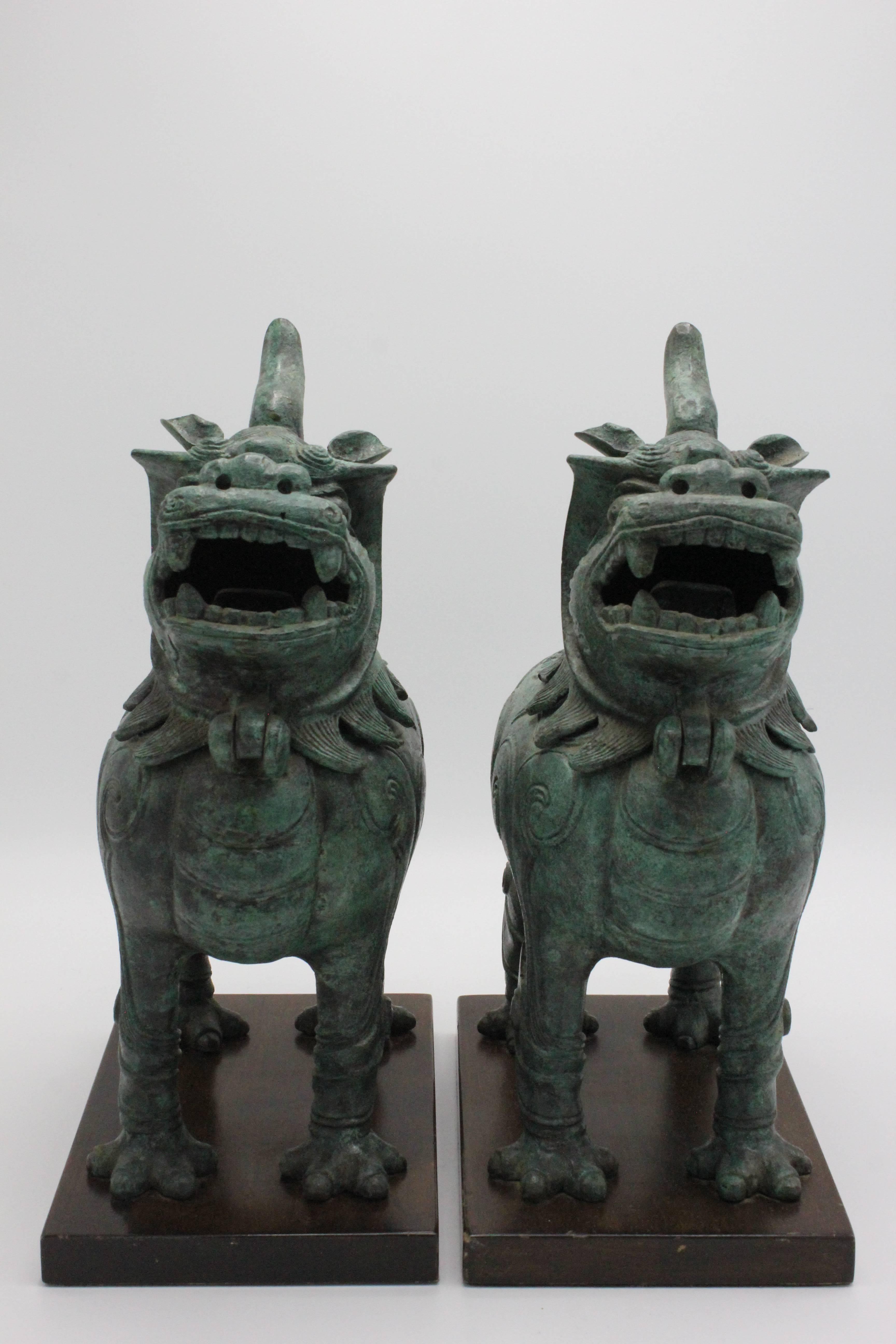 Pair of Frederick Cooper foo dog sculptures on wood bases. The head of each dog tilts back for use as an incense burner. Each pieces weighs approx. 14 pounds. Frederick Cooper label affixed underneath.