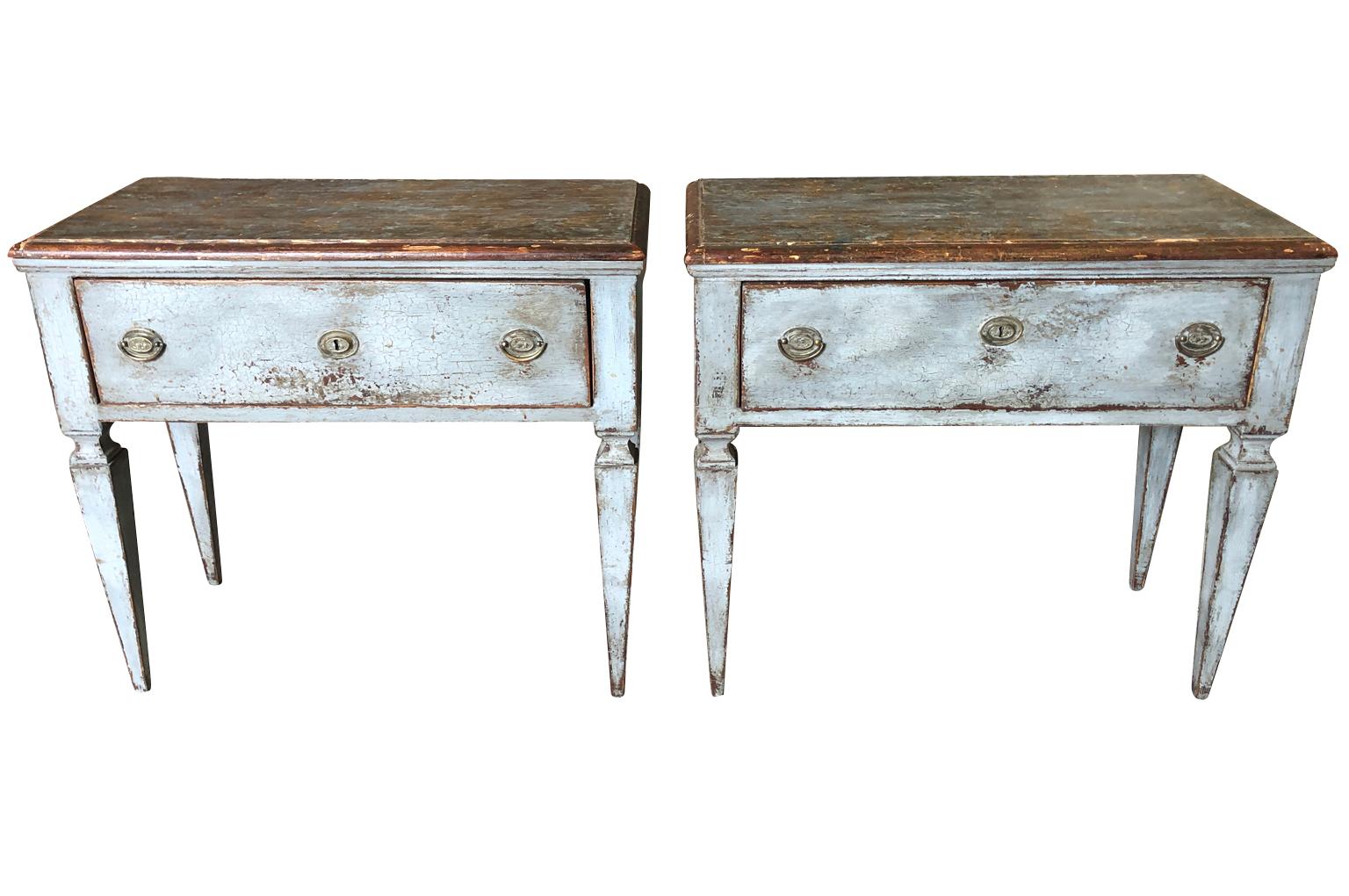 A charming pair of side tables - consoles from the South of France constructed from painted wood with a single drawer on tapered legs and finished on all sides. Lovely patina. Perfect not only as end tables, but terrific as bedside tables as well.