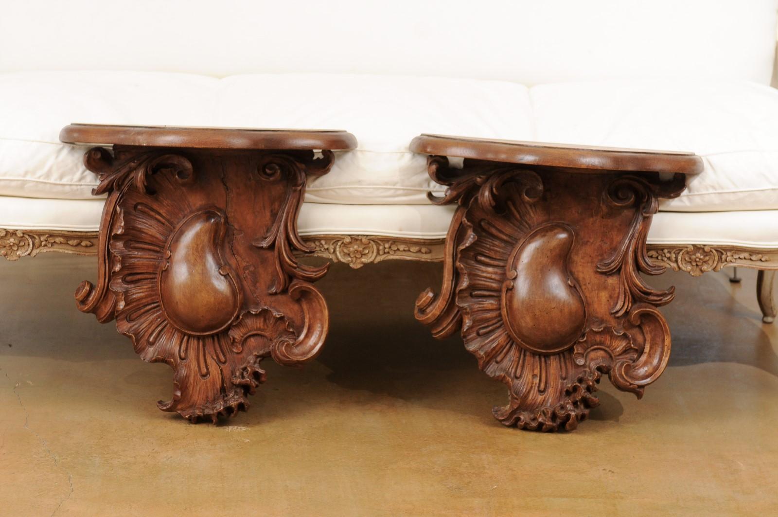 A pair of French Louis XV period mid-18th century walnut wall brackets from Lyon with Rocailles motifs. Created in Lyon during the third quarter of the 18th century, each of this pair of wall brackets features a shaped top sitting above a nicely