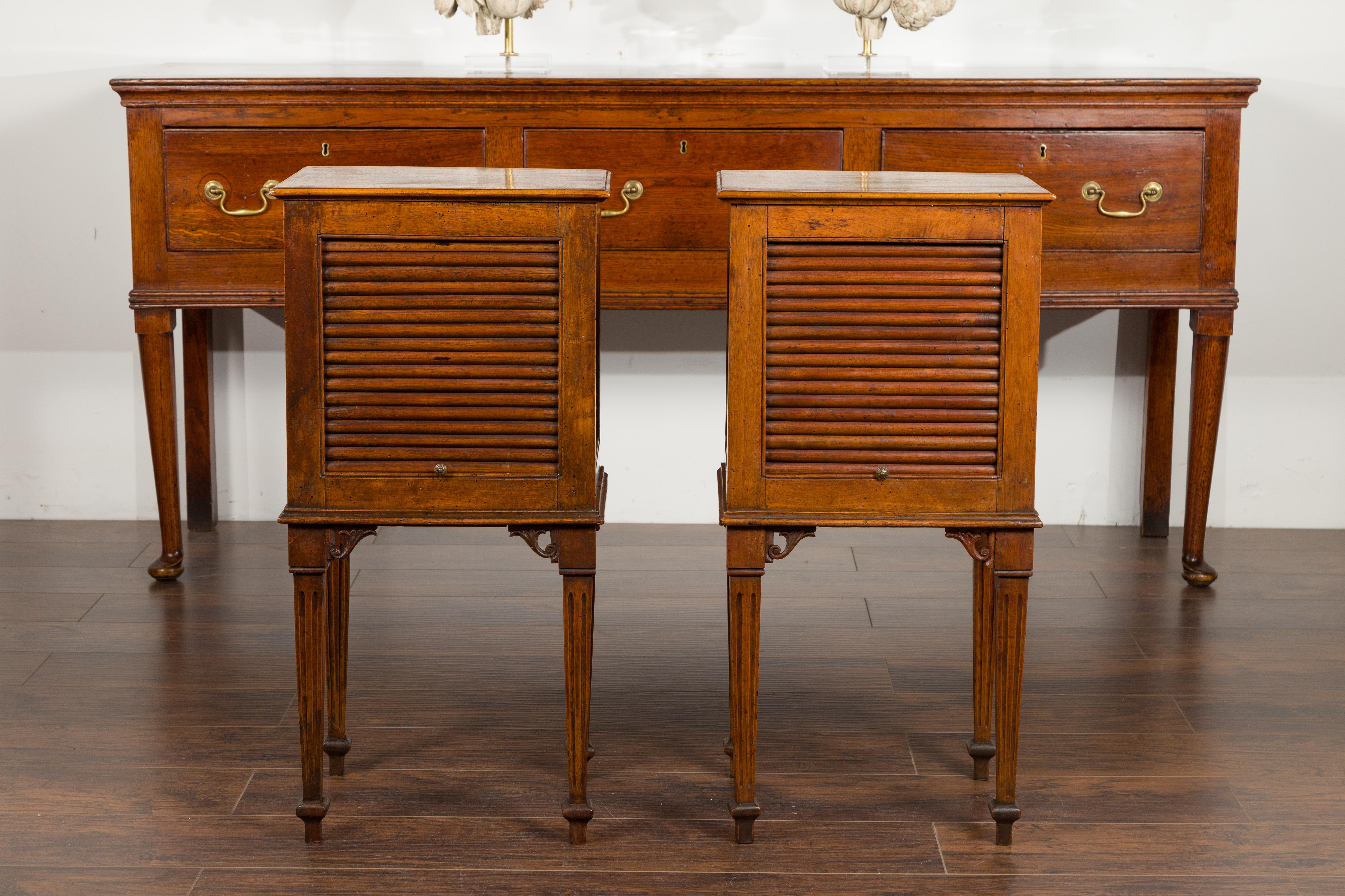 A pair of French Restauration period walnut tambour door tables from the mid-19th century, with tapered fluted legs. Created in France during the Restauration period, each of this pair of walnut tables features a rectangular top sitting above a