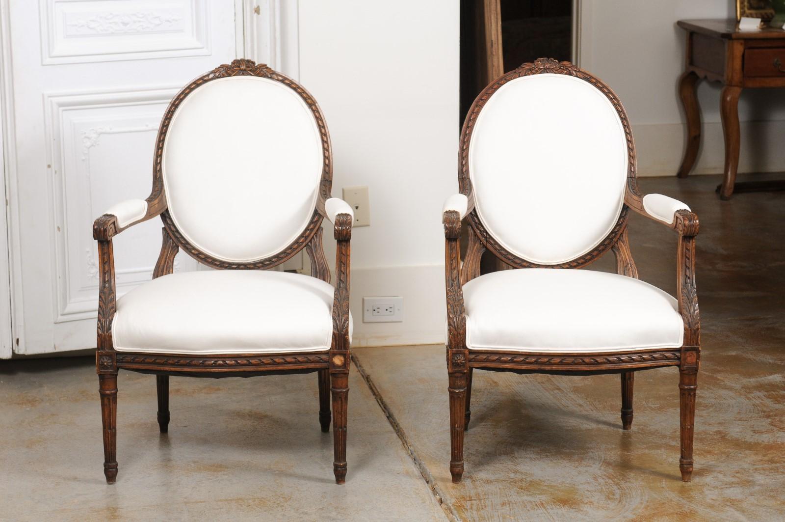 Carved Pair of French 1850s Louis XVI Style Walnut Oval Back Upholstered Armchairs For Sale