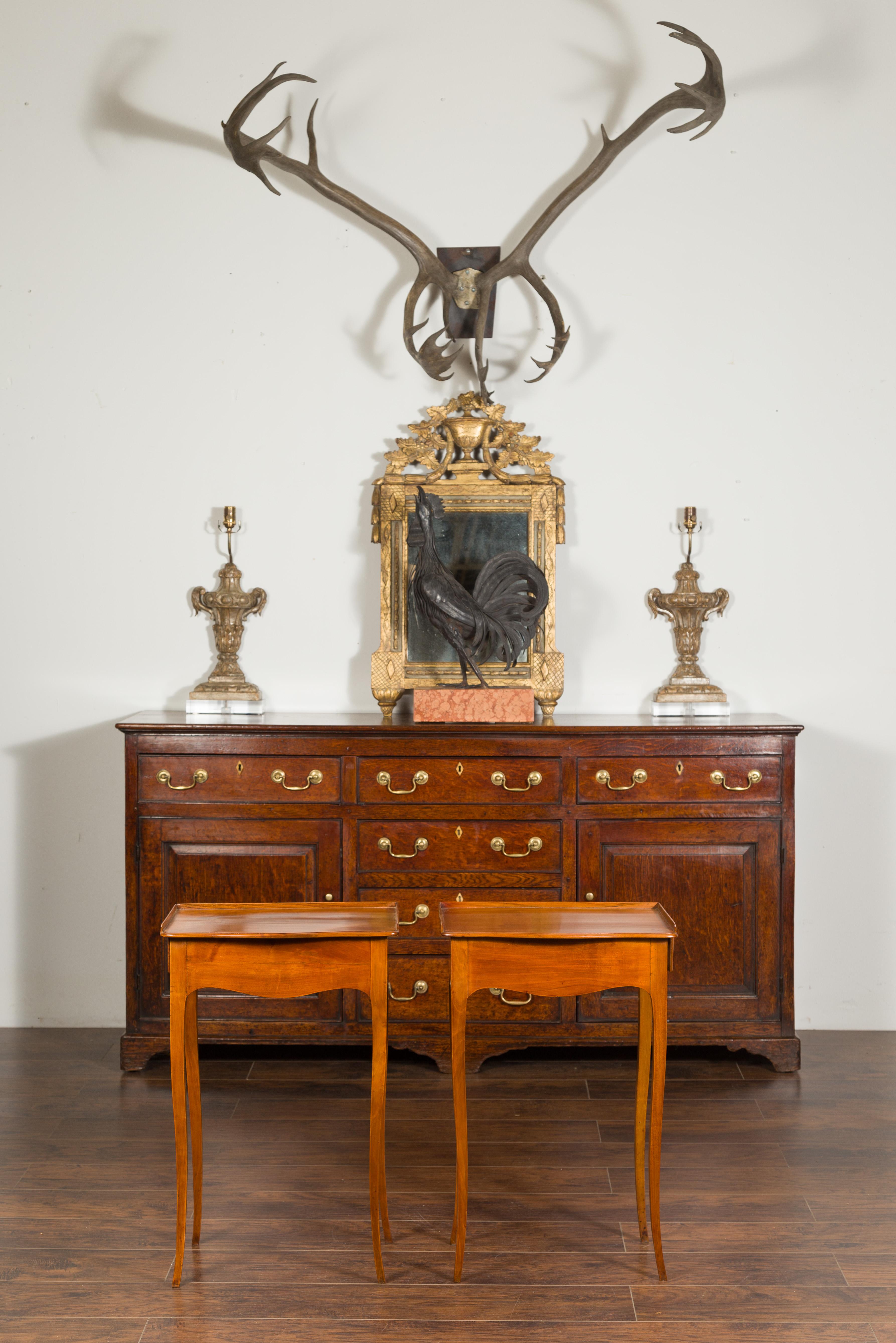 A pair of French Napoleon III period walnut side tables from the mid-19th century, with lateral drawers and scalloped aprons. Created in France during the reign of Emperor Napoleon III, each of this pair of side tables features a rectangular top