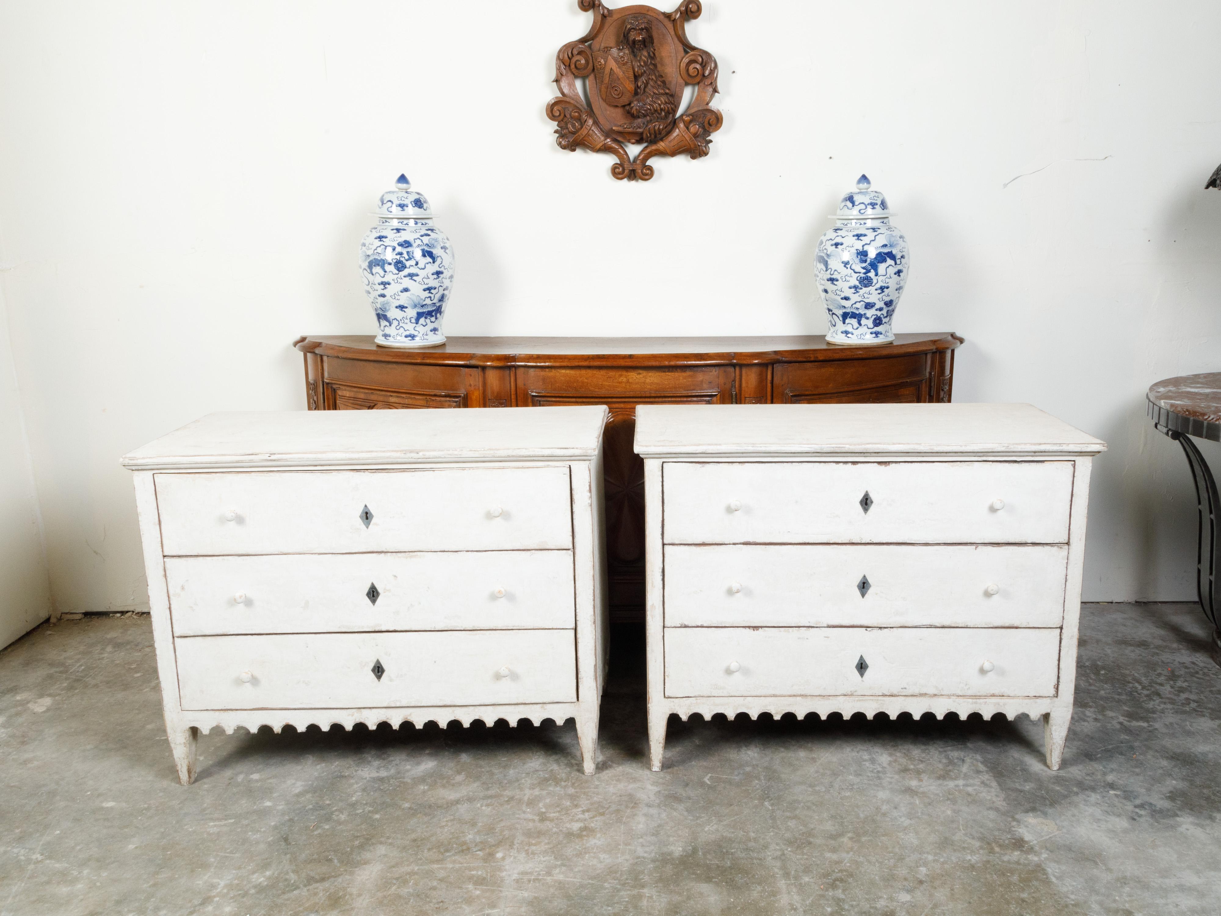 A pair of French three-drawer commodes from the late 19th century, with new paint and scalloped skirt. Created in France during the third quarter of the 19th century, each of this pair of painted commodes features a rectangular top sitting above a