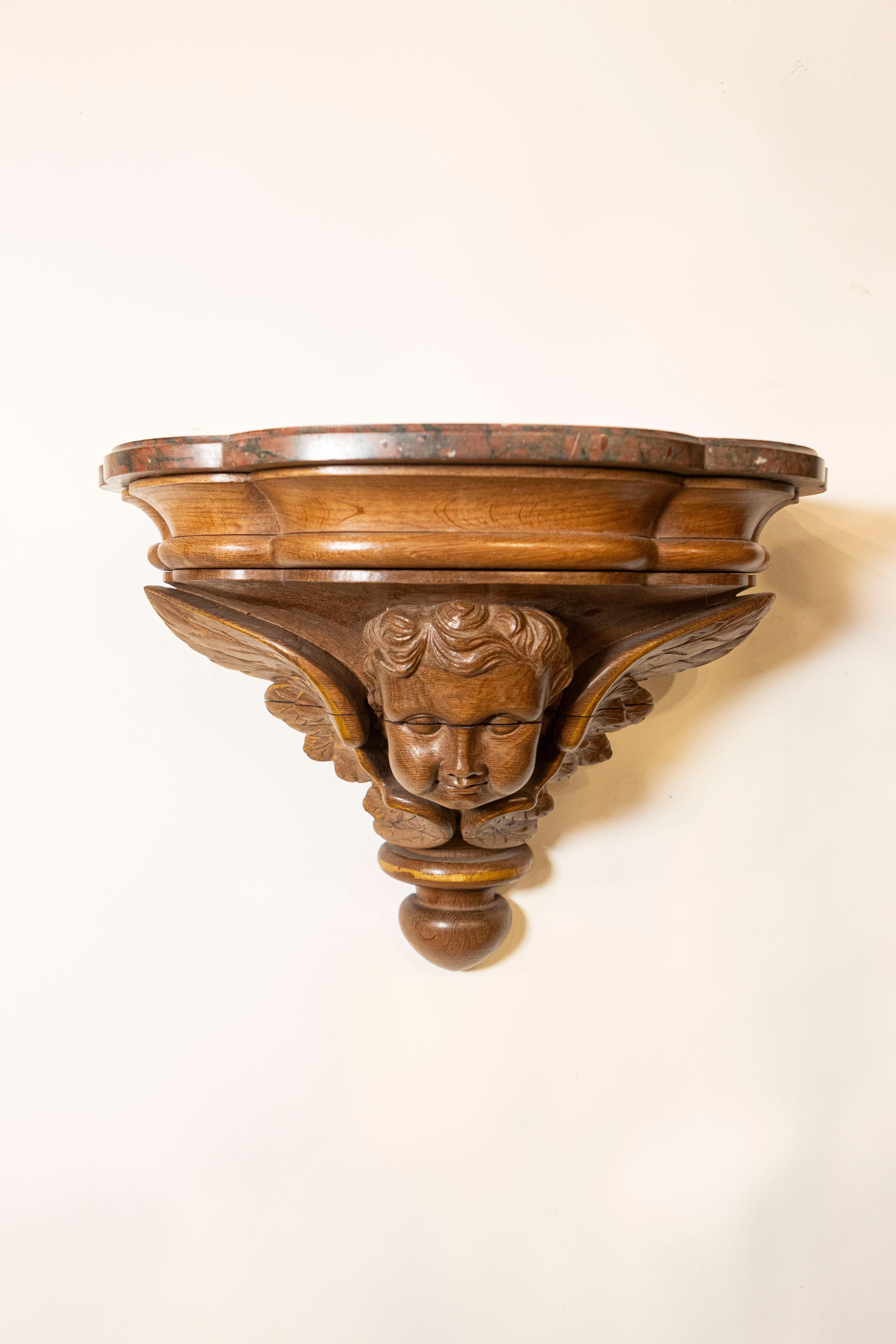 A pair of French carved walnut brackets from the late 19th century, with cherubs and faux marble tops. Created in France during the last quarter of the 19th century, each of this pair of walnut wall consoles features a shaped faux-marble top sitting