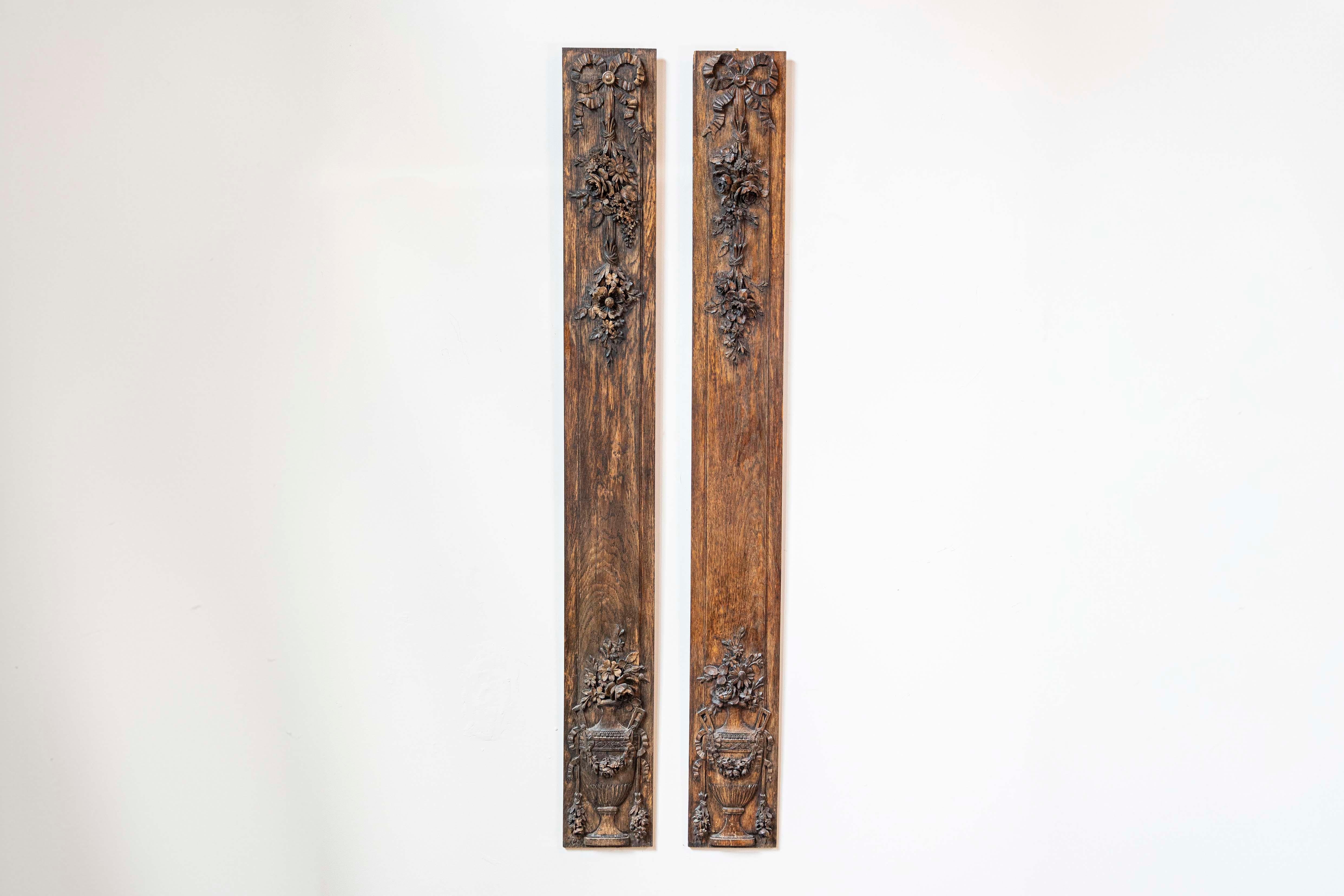 A pair of French vertical carved wooden panels from the late 19th century, with ribbon-tied floral bouquets and urns. Created in France during the last decade of the 19th century, each of this pair of carved panels features a delicate low-relief