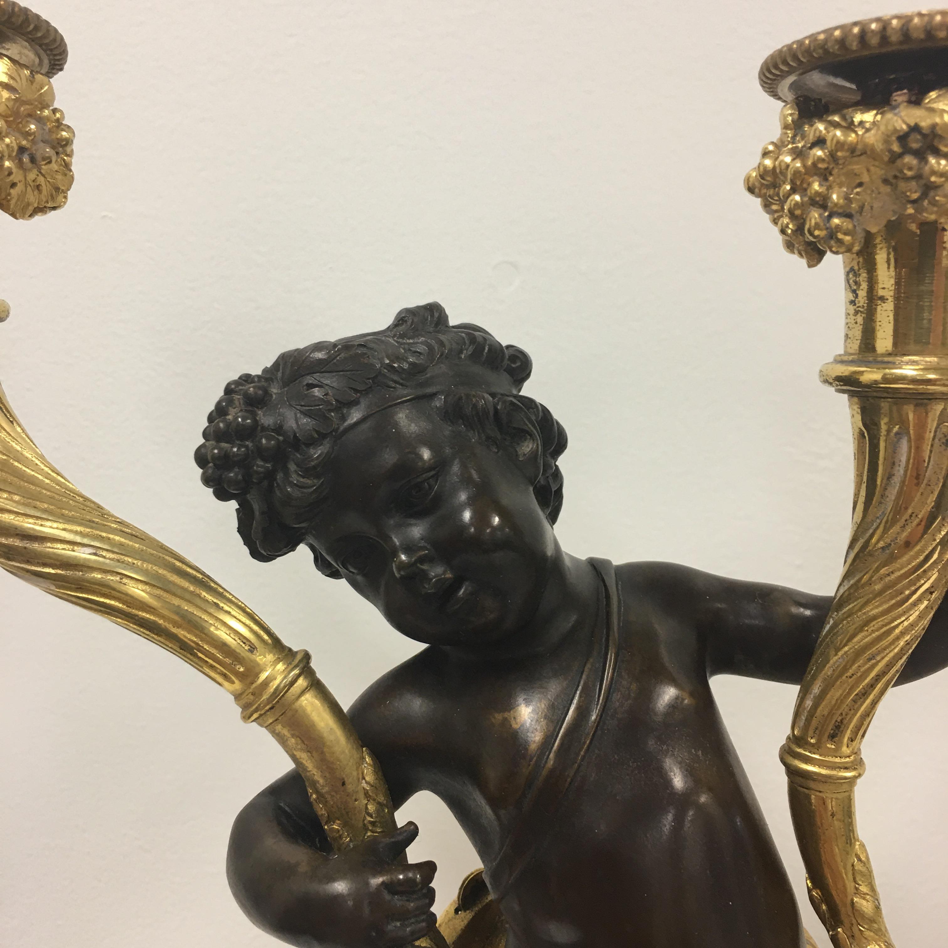 A fine pair of French 18th century Louis XV period, mercury gilt and patinated bronze candelabras.  At the center are charming jubilant cherubs each holding a richly chased branch supporting a single candle cup in each hand.  The cherubs are