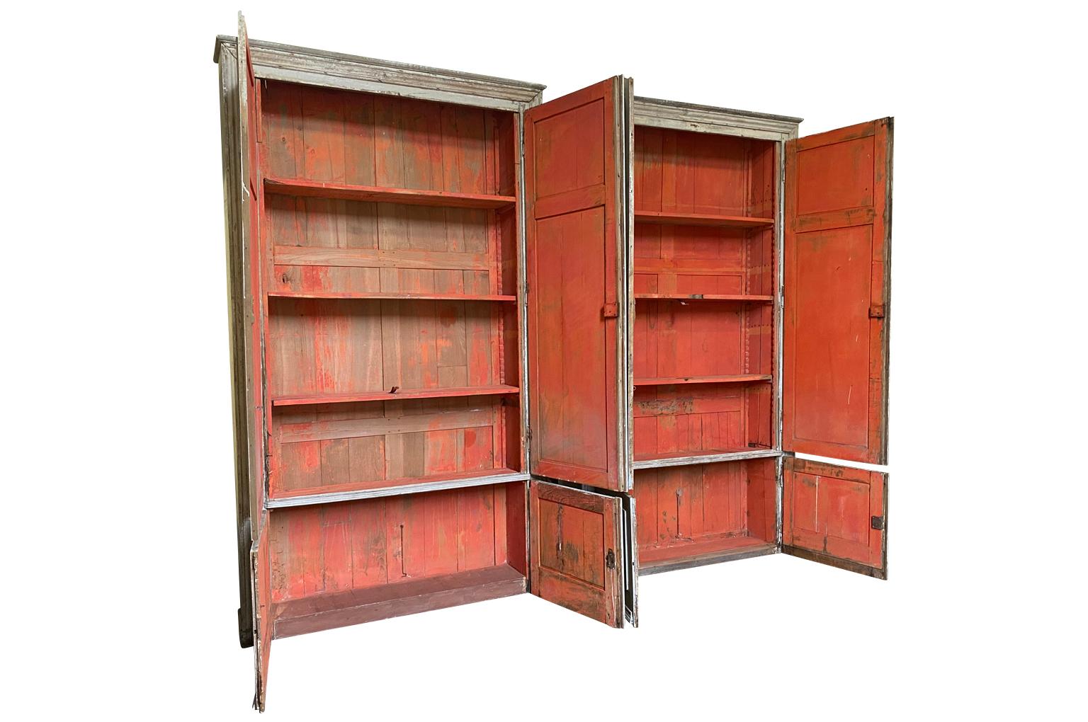 A wonderful pair of 18th century armoires from the South of France. Beautifully constructed from painted wood - each with 4 doors and a stunning orange interior. Great narrow depth. Excellent storage pieces for any living or bedroom area. One