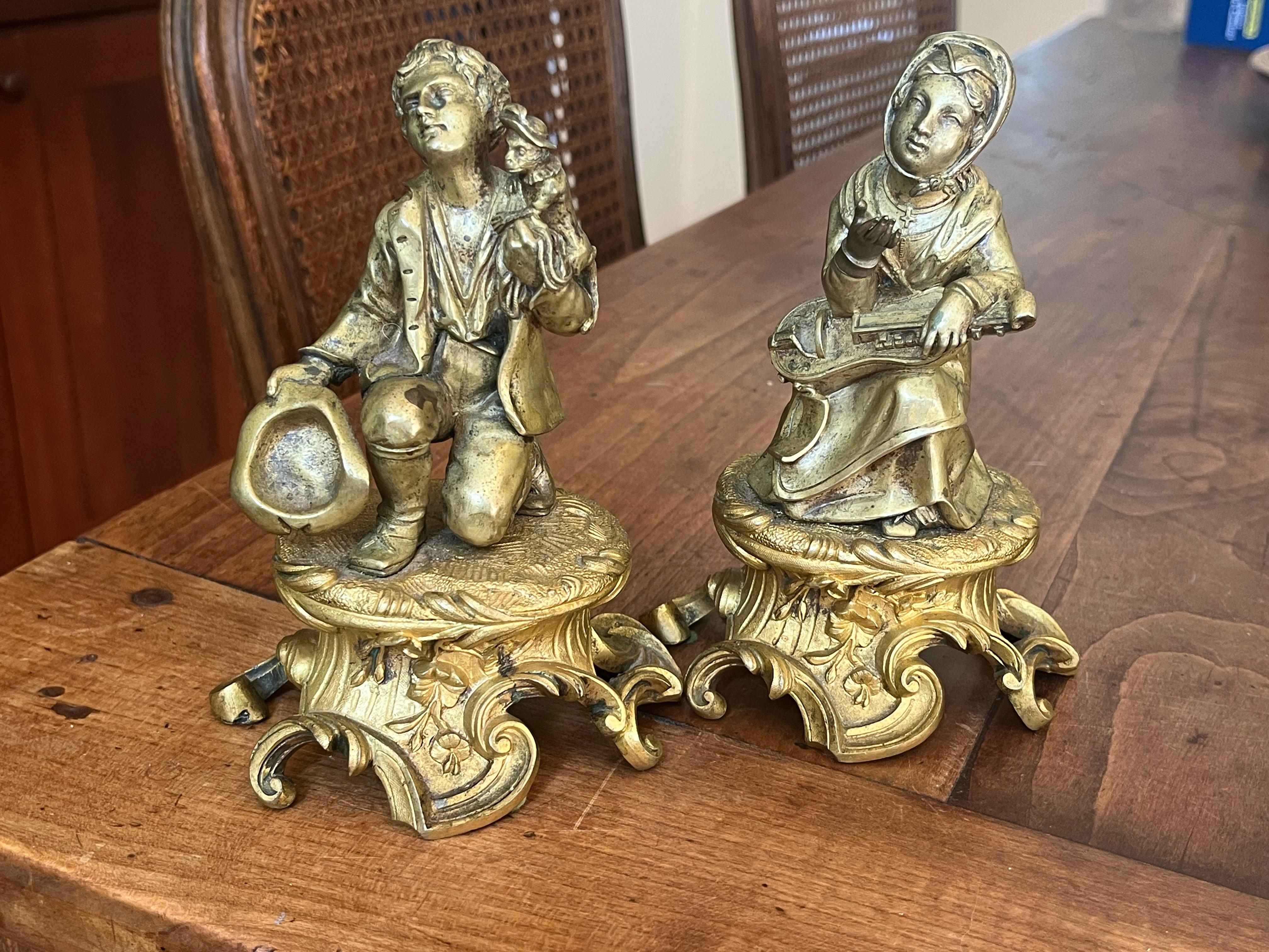 A charming pair of 18th century bronze figures depicting a peasant couple, the female playing a lute and the male with a monkey on his shoulder and holding his hat, mounted on gilt-bronze bases.