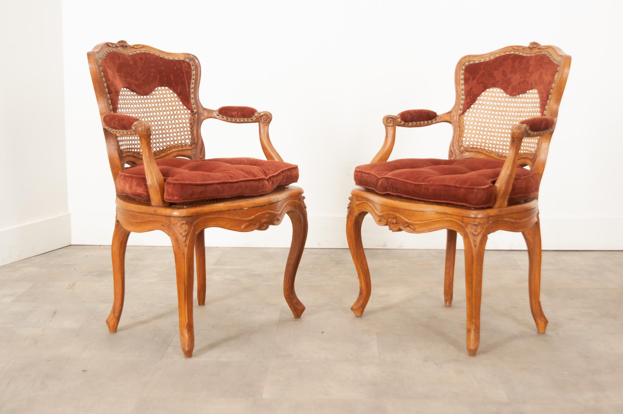 A pair of 18th century Louis XV style oak frame chairs. Upholstered with burgundy velvet fabric, the seat height is 16 ¾” without the cushion and 19 ⅛” with the cushion. The caning is in overall great condition, stained to match the rich oak. There