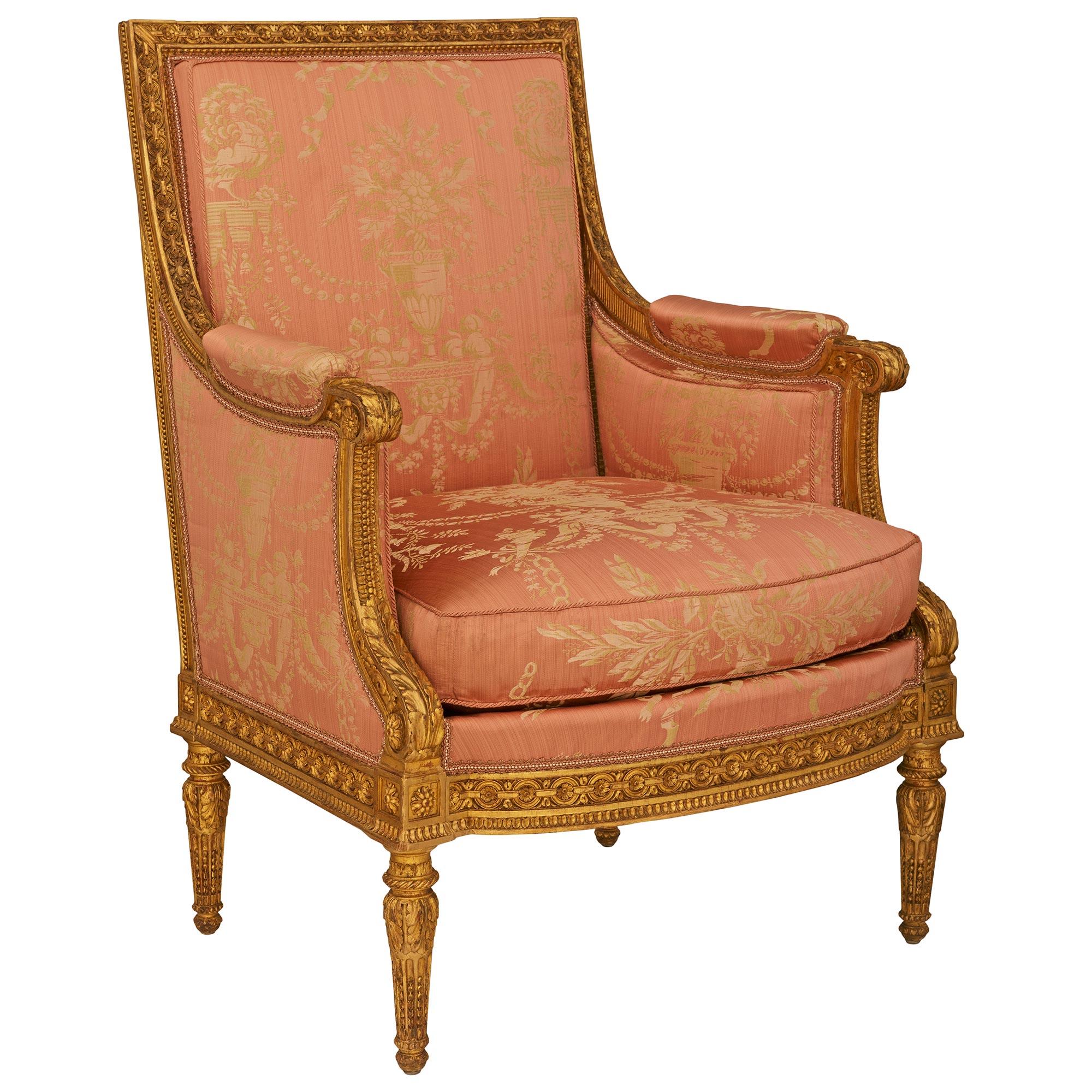 Un par de sillones Bergère franceses de madera dorada del periodo Luis XVI, de gran calidad y elegancia. Este impresionante par de sillones se elevan sobre cuatro patas cónicas circulares en forma de toupie, decoradas con flautas y chandelas