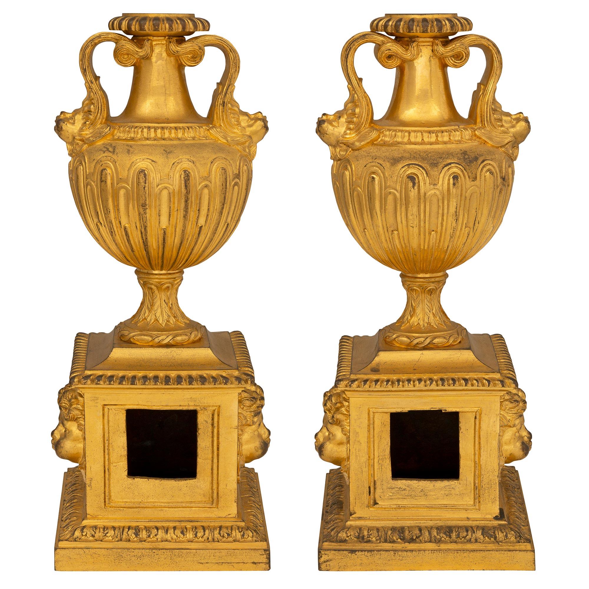 Une paire très élégante de Chenets/andrônes de cheminée en bronze doré d'époque Louis XVI du 18ème siècle. Chaque Chenet est surélevé par une base carrée avec une bordure enveloppante de feuilles d'acanthe. Au centre, trois charmants visages