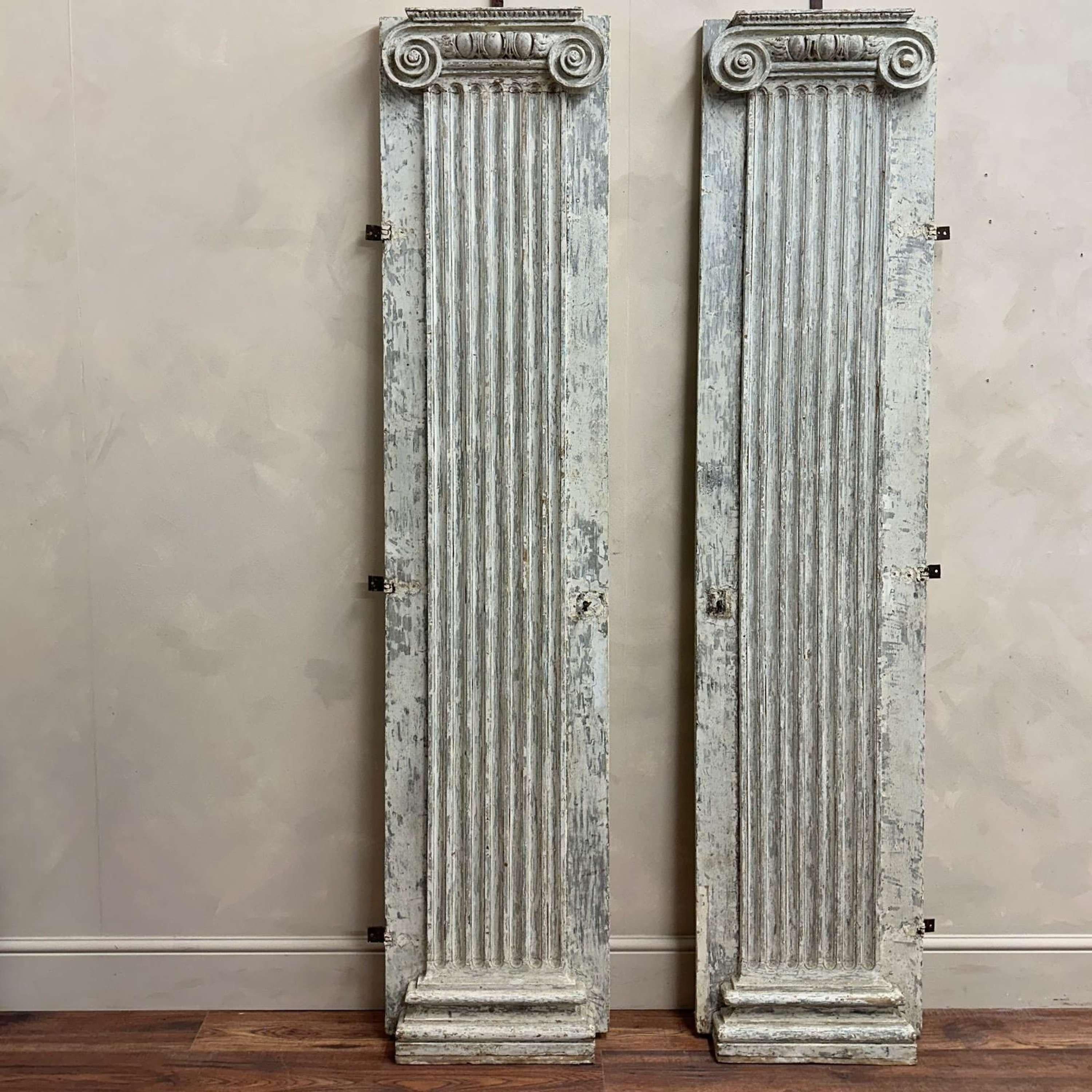 A pair of wooden, hand carved columns with roman ionic capitals and fluted pedistals.
These were  originally part of a large bookcase, built within the walls of a chateau in France.
Wonderful scraped paint, original hinges still attached.
These