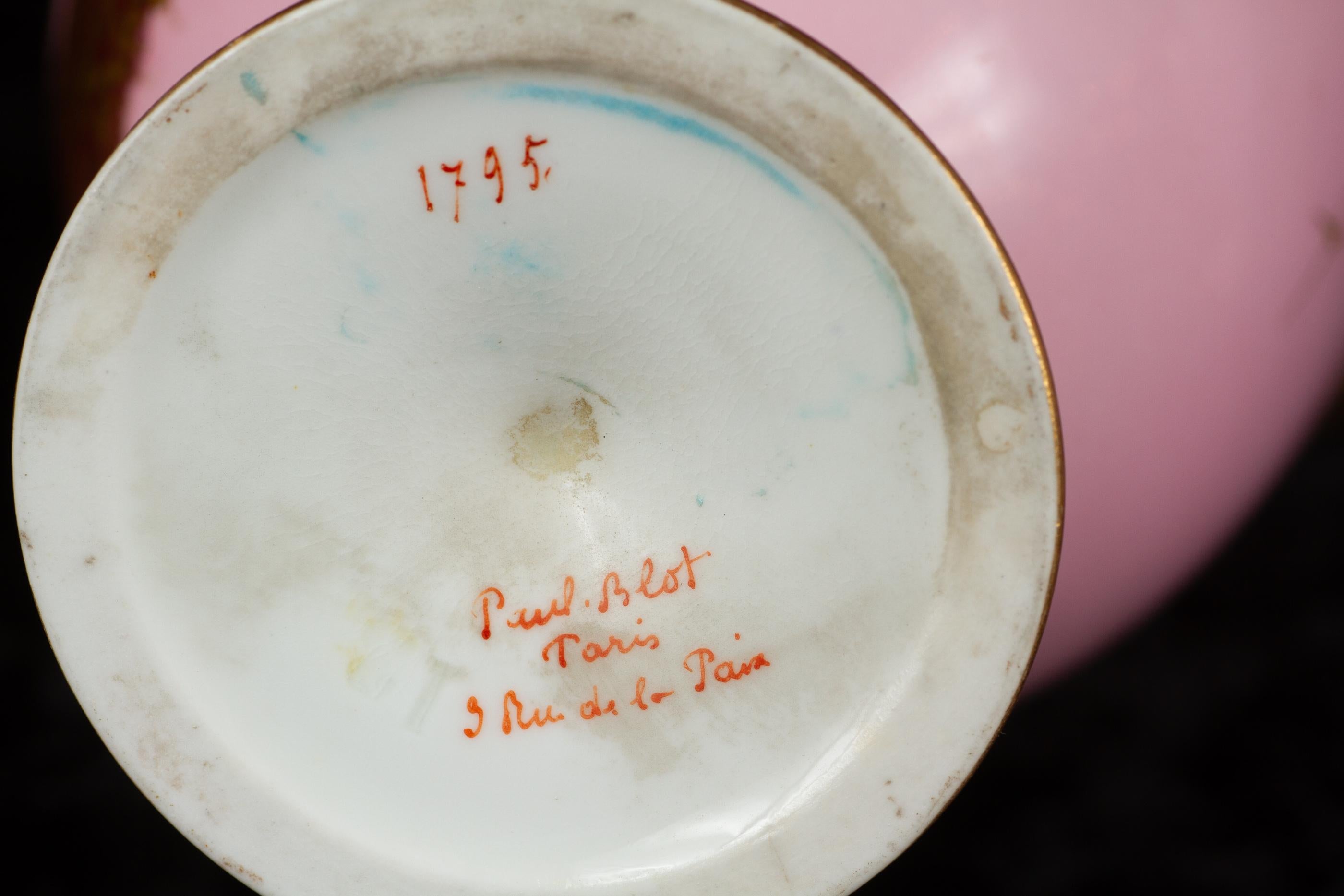 Paire de vases à pied en porcelaine rose pâle du XVIIIe siècle en forme d'urnes grecques, avec une anse en or de chaque côté.  

Le dessus, le dessus du pied,  ainsi que le fond sont richement ornés d'or.  Les motifs au centre sont un palmier, du