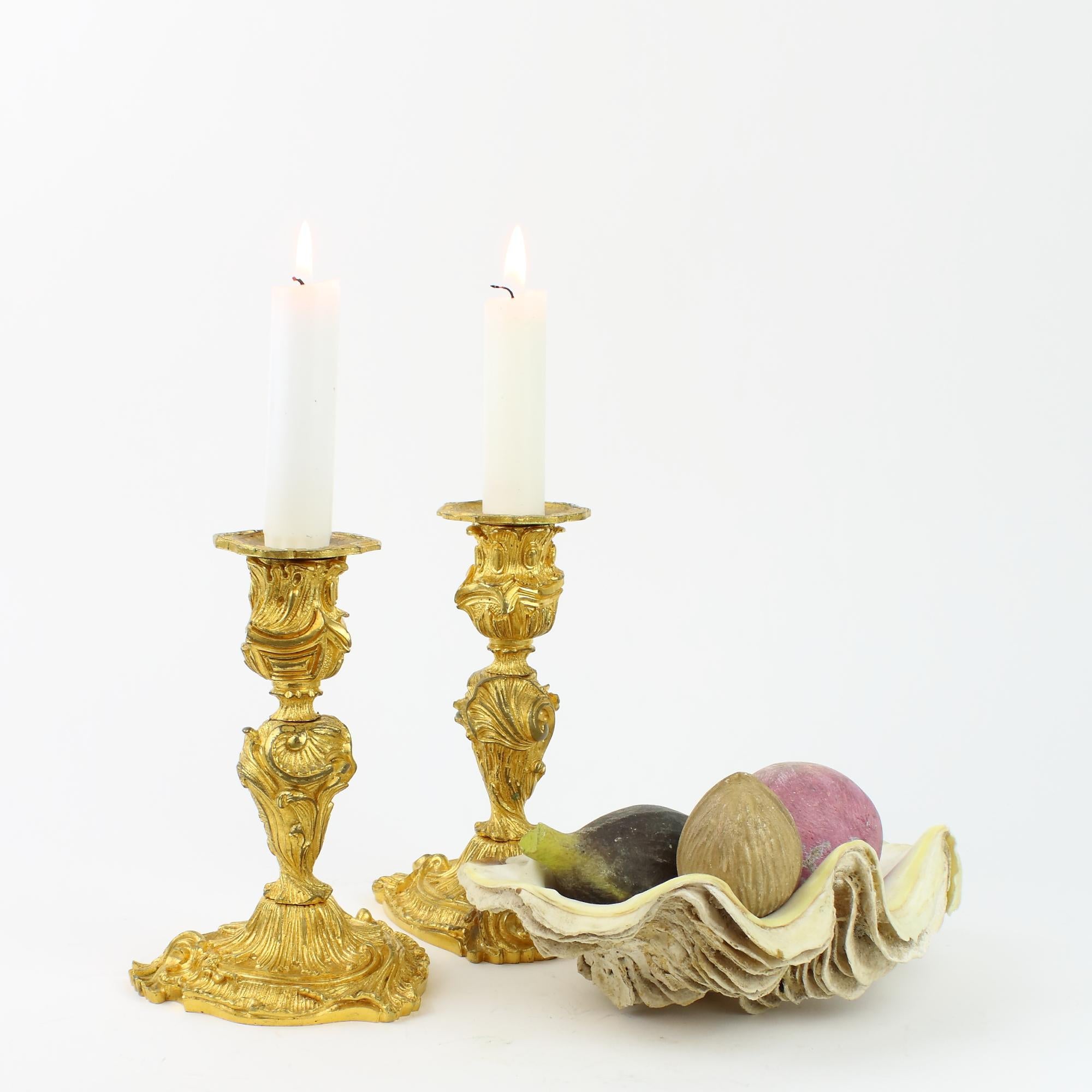 Pair of French 18th Century Small Louis XV Gilt Bronze Candlesticks

Short stem of swirling asymmetrical Rococo form with shell-like and foliage decoration, conforming nozzle and foliate, removable drip-pan, above a rounded triangle-shaped base with