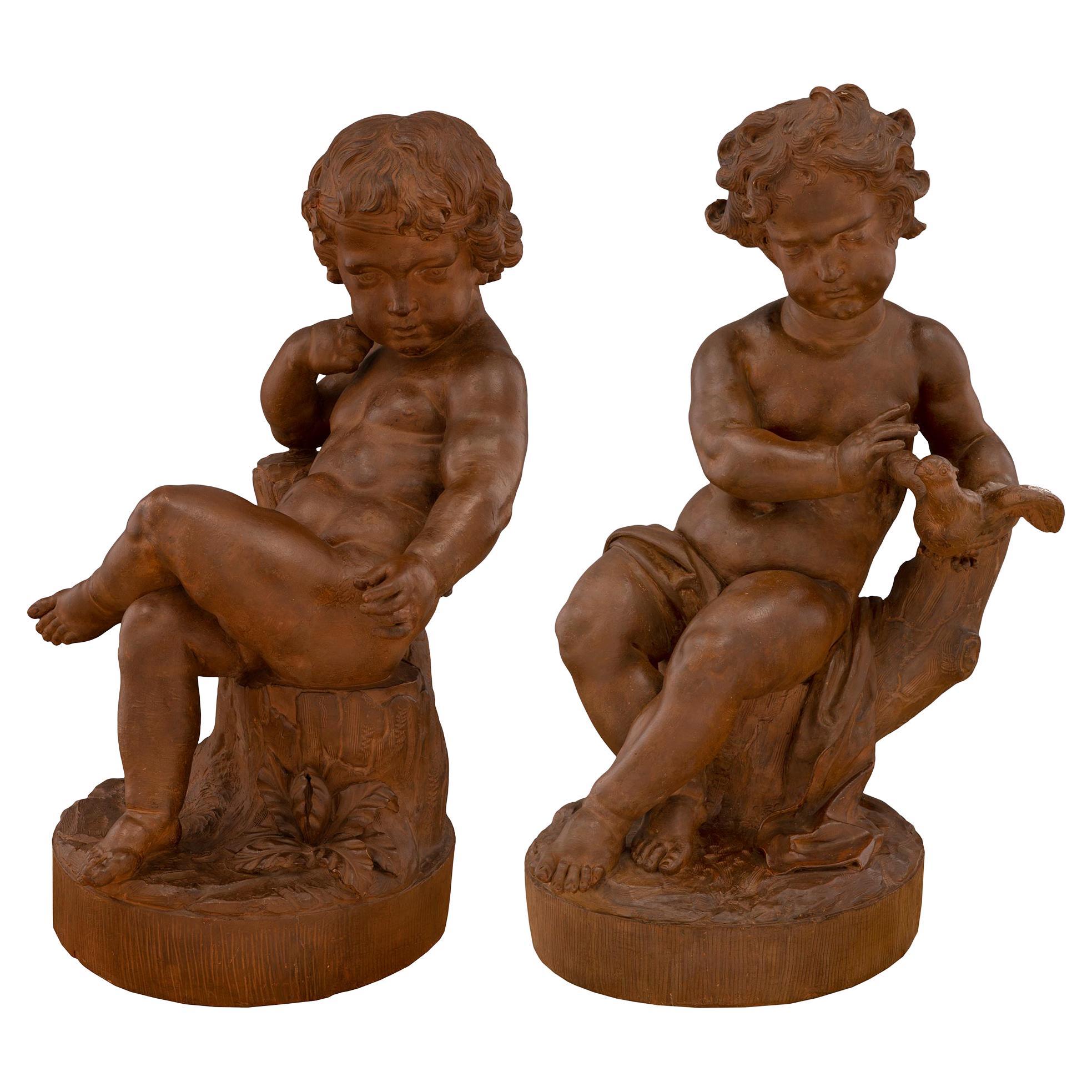 Paire de statues françaises en terre cuite du 18e siècle représentant des enfants jouant avec un oiseau