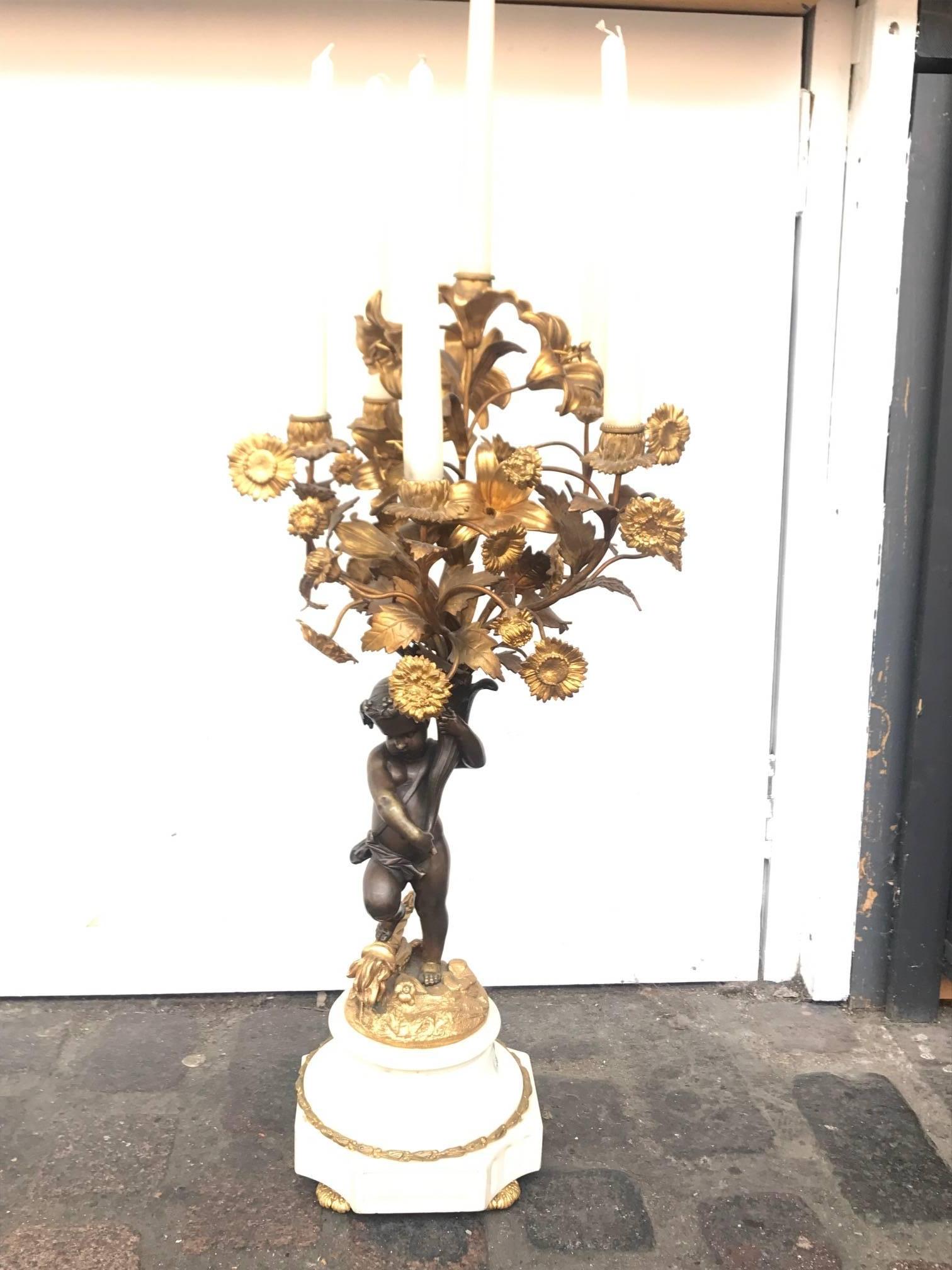 Paire de candélabres en bronze coulé en forme de putti (chérubin), datant du XIXe siècle. Les candélabres à quatre branches sont ornés d'un chérubin debout tenant un bouquet de lys, de marguerites et de feuilles en bronze doré. Tous deux reposent