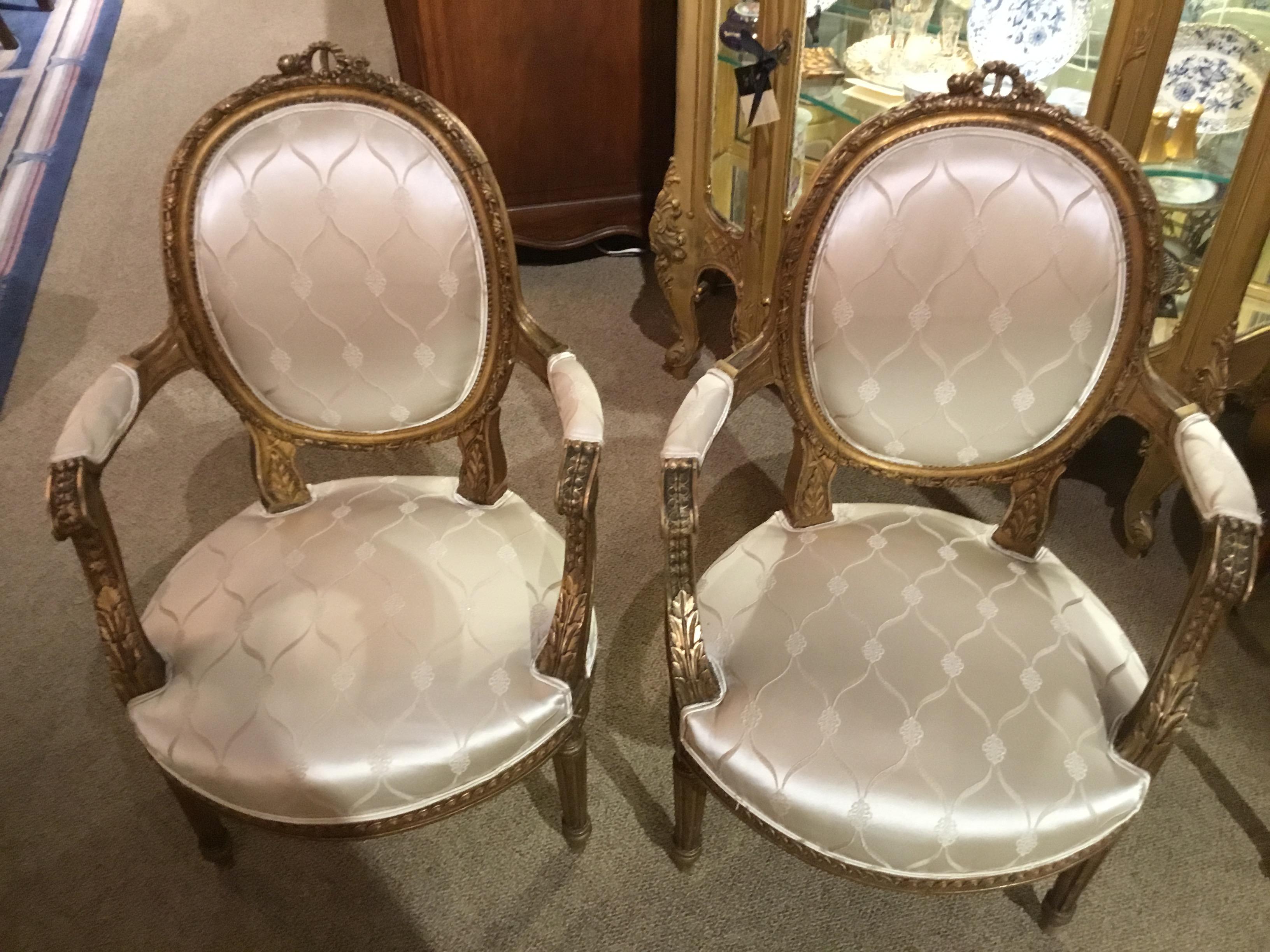 Pair of Louis XVI style 19th century giltwood armchairs with new white silk
Upholstery. Having a reed leg. Oval back with a lovely carved crest at the
Top center.