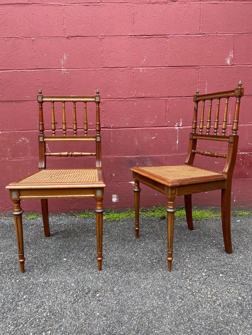 An exceptional pair of French 1900s neoclassical style side chairs with caned seats and brass detailing. This pair of neoclassical style side chairs offers a unique and sophisticated look for any space. The caned seats and brass detailing provide an