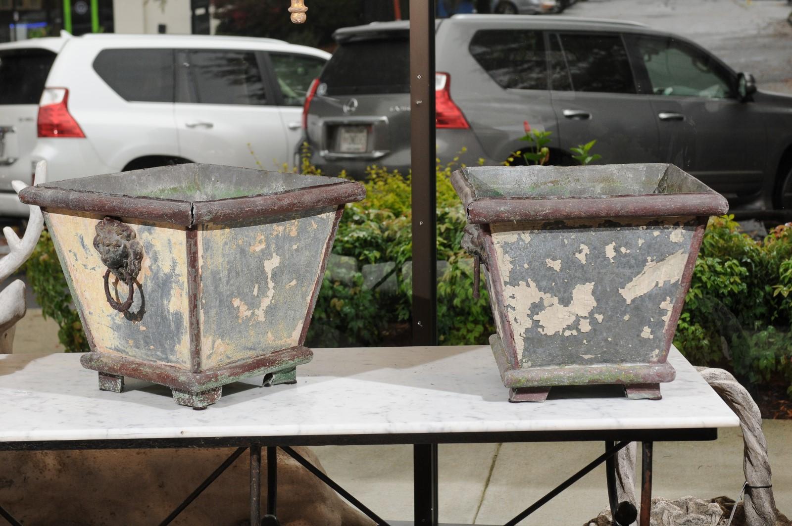 A pair of French zinc planters from the early 20th century with original liners. Born in France at the turn of the century, each of this pair of planters features a square, tapering body that is raised on four petite feet. Marked by large edges at