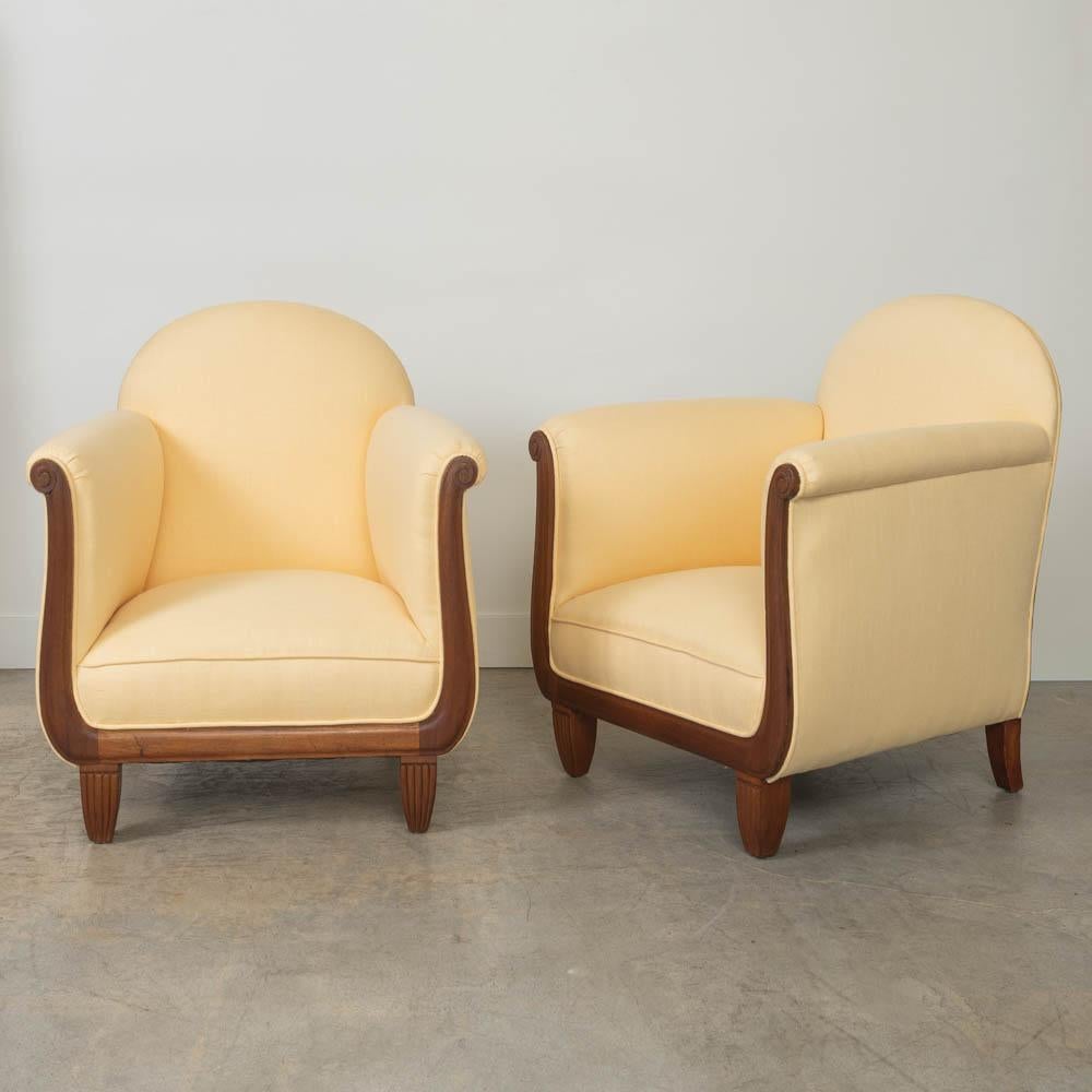 Incredibile coppia di sedie da club Art Déco provenienti dalla Francia, anni '20. Bellissima cornice in legno curvato con dettagli a voluta sui braccioli. Rivestito di recente in un delizioso lino giallo pallido. La finitura originale del legno