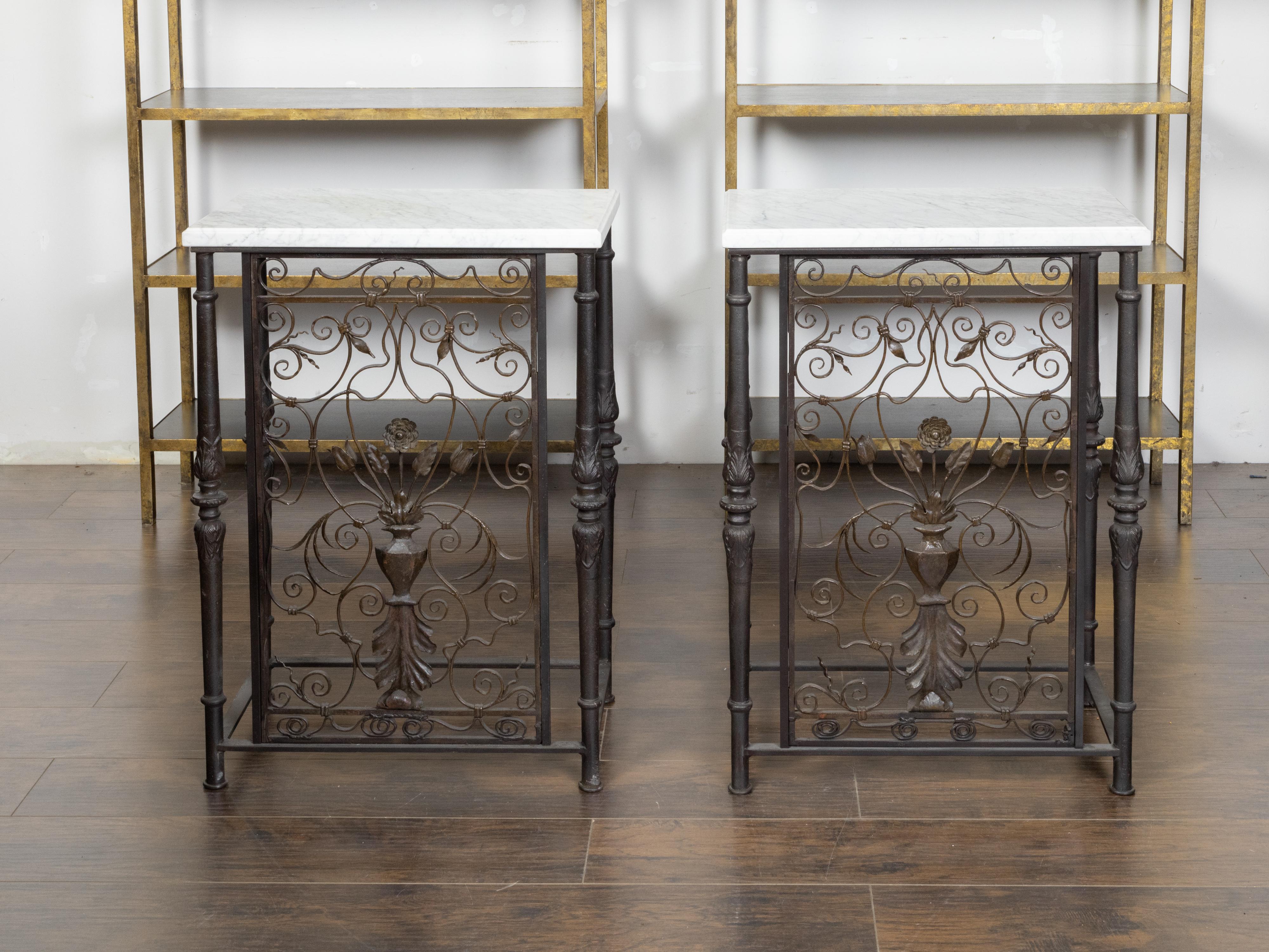 A pair of French iron console tables from the early 20th century, with white marble tops and petite bouquets of flowers. Created in France during the Roaring Twenties, each of this pair of iron console tables features a rectangular white veined