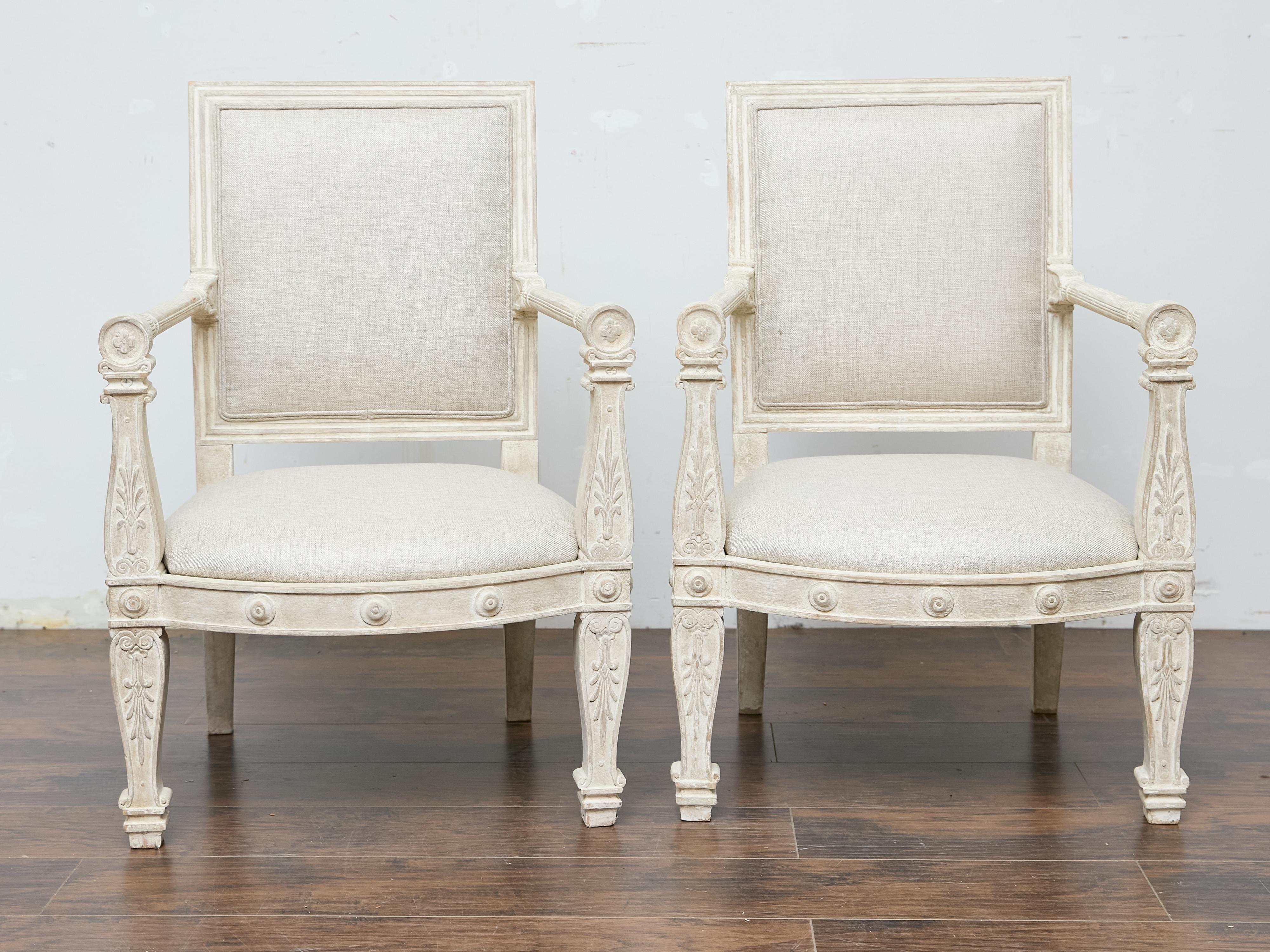 These French armchairs from circa 1920 embody the refined elegance of the Louis XVI style with their neoclassical proportions and crisp detailing. Crafted from solid beechwood, the frames are hand-carved with delicate rosettes, acanthus leaves, and