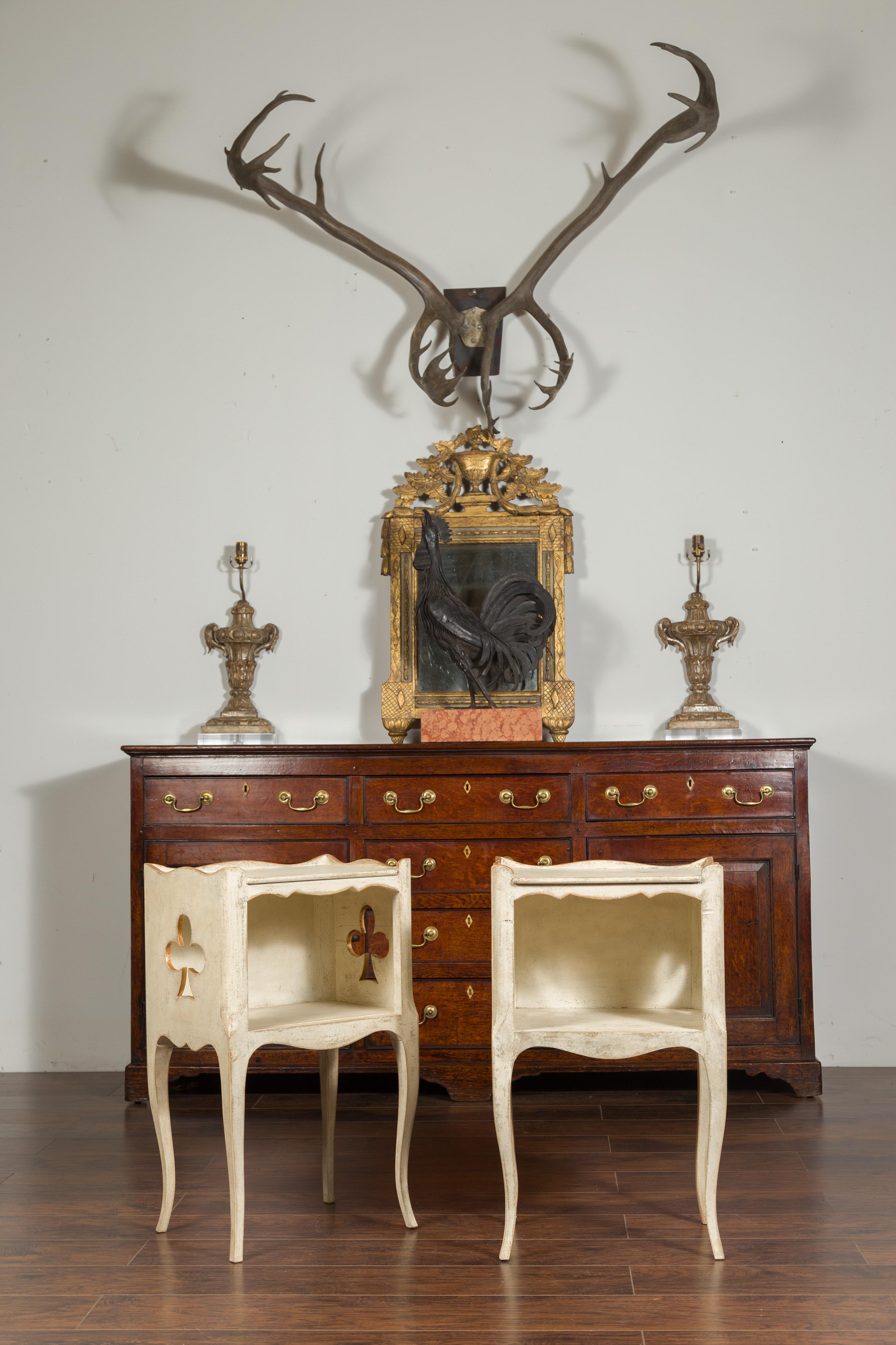 A pair of French bedside tables from the early 20th century, with pierced clubs and freshly repainted. Created in France during the first quarter of the 20th century, each of this pair of side tables features a rectangular top surrounded by a