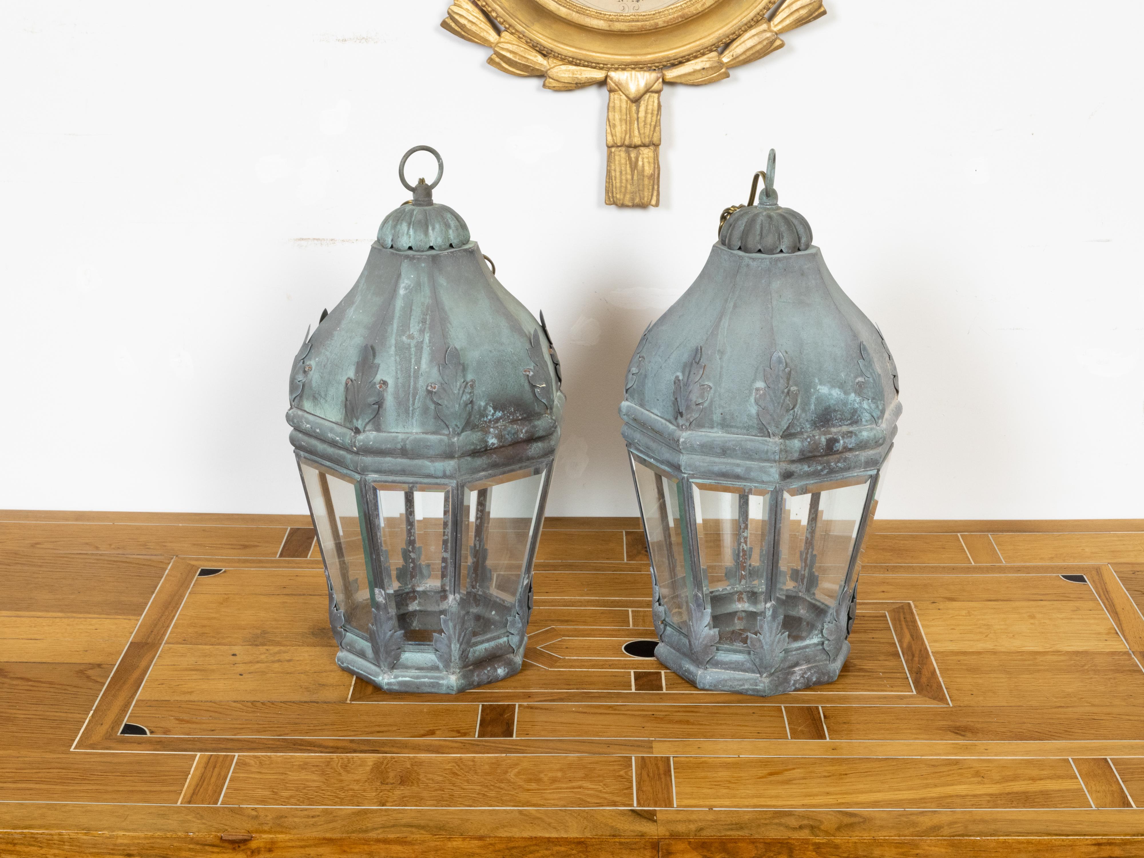 A pair of French octagonal copper lanterns from circa 1940 with foliage motifs and glass panels. Illuminate your home with the timeless charm of this pair of French octagonal copper lanterns from circa 1940, a duo that masterfully blends the allure
