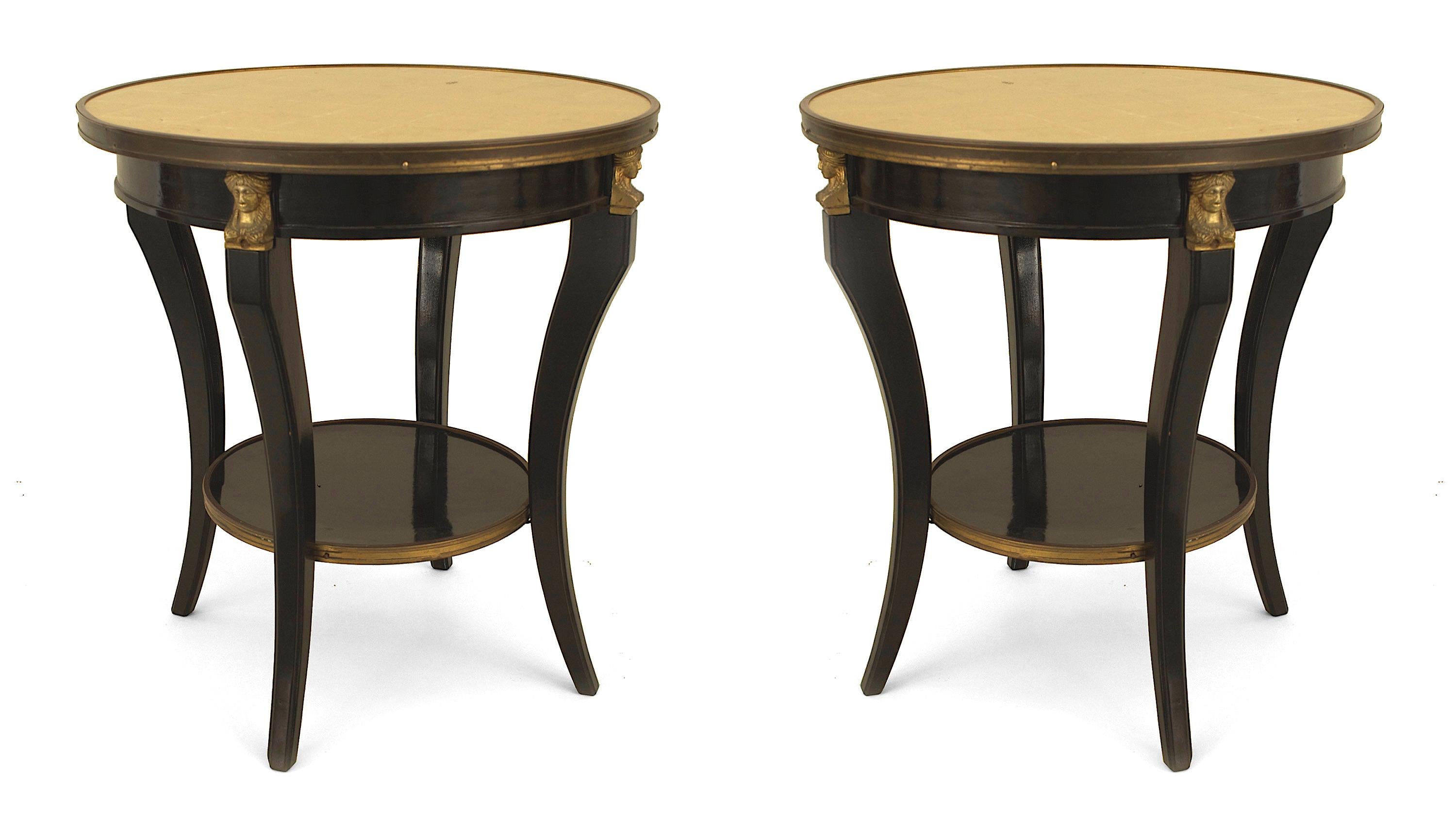 Pair of French 1940s (Louis XVI style) ebonized and bronze trimmed round end tables with four concave legs supported by a round shelf stretcher and gilt glass inset tops (stamped: JANSEN).

Maison Jansen was a Paris-based interior decoration office