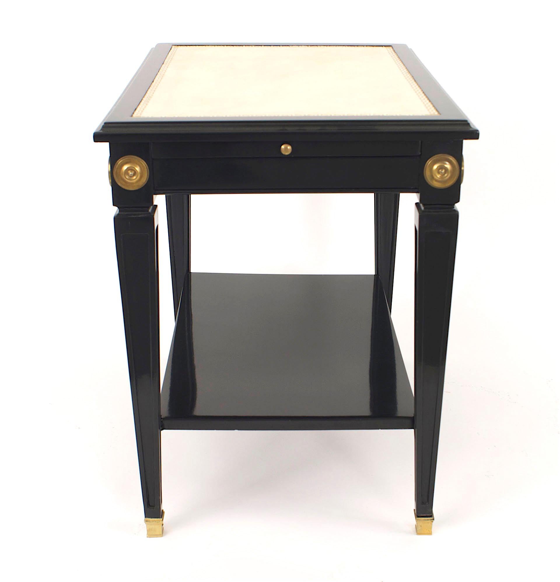 Pair of French Louis XVI-style (1940s) ebonized and bronze trimmed low end tables with a shelf and white inset leather top with a matching slide shelf on square tapered legs. (Stamped: MAISON JANSEN) (PRICED AS Pair)
