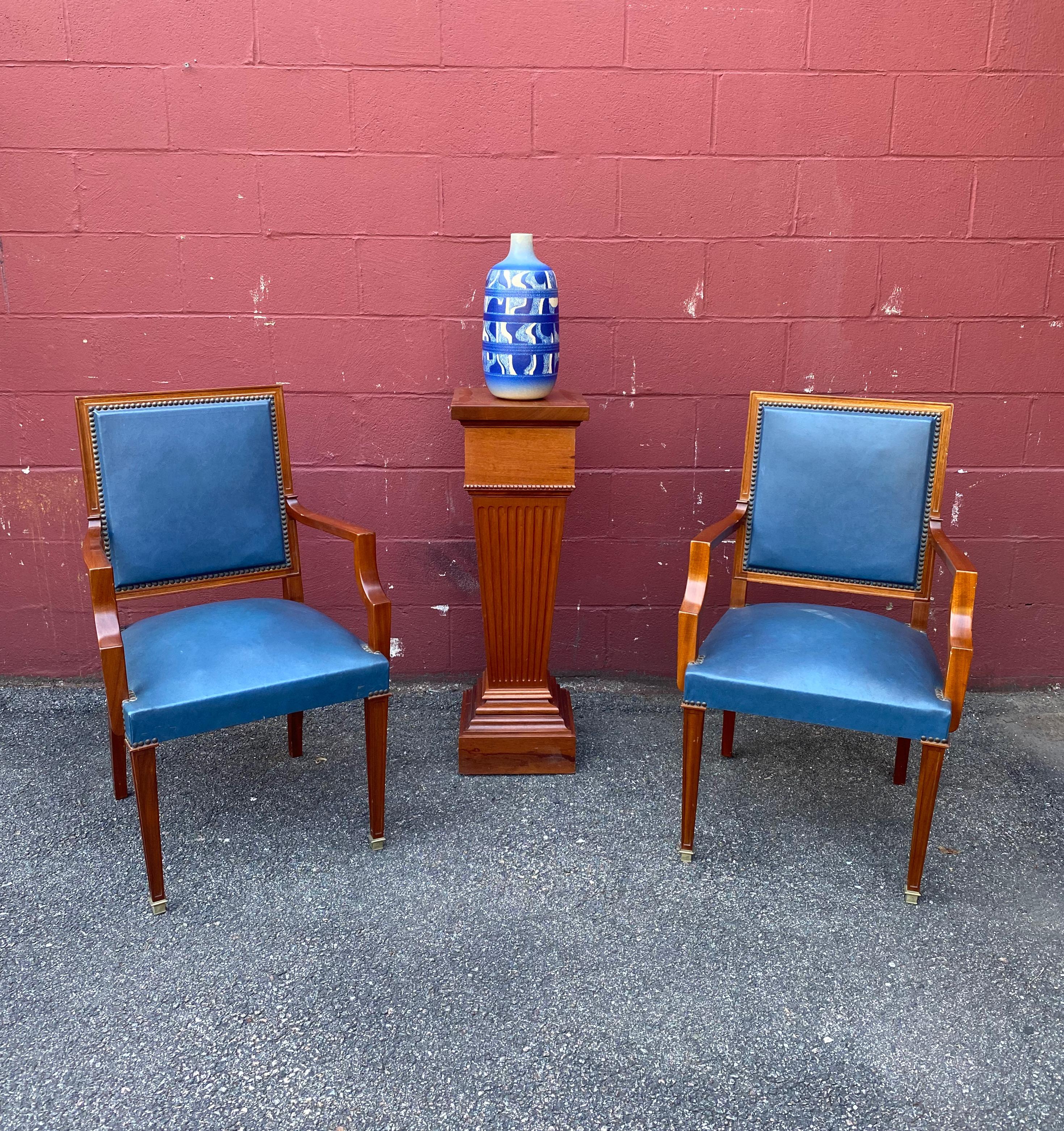 A stunning pair of French 1940s armchairs in blue leather. Experience classic French luxury with this timeless pair of 1940s armchairs. The sleek mahogany wood frames offer an elegant presence with their rich color and brass nailing, while the