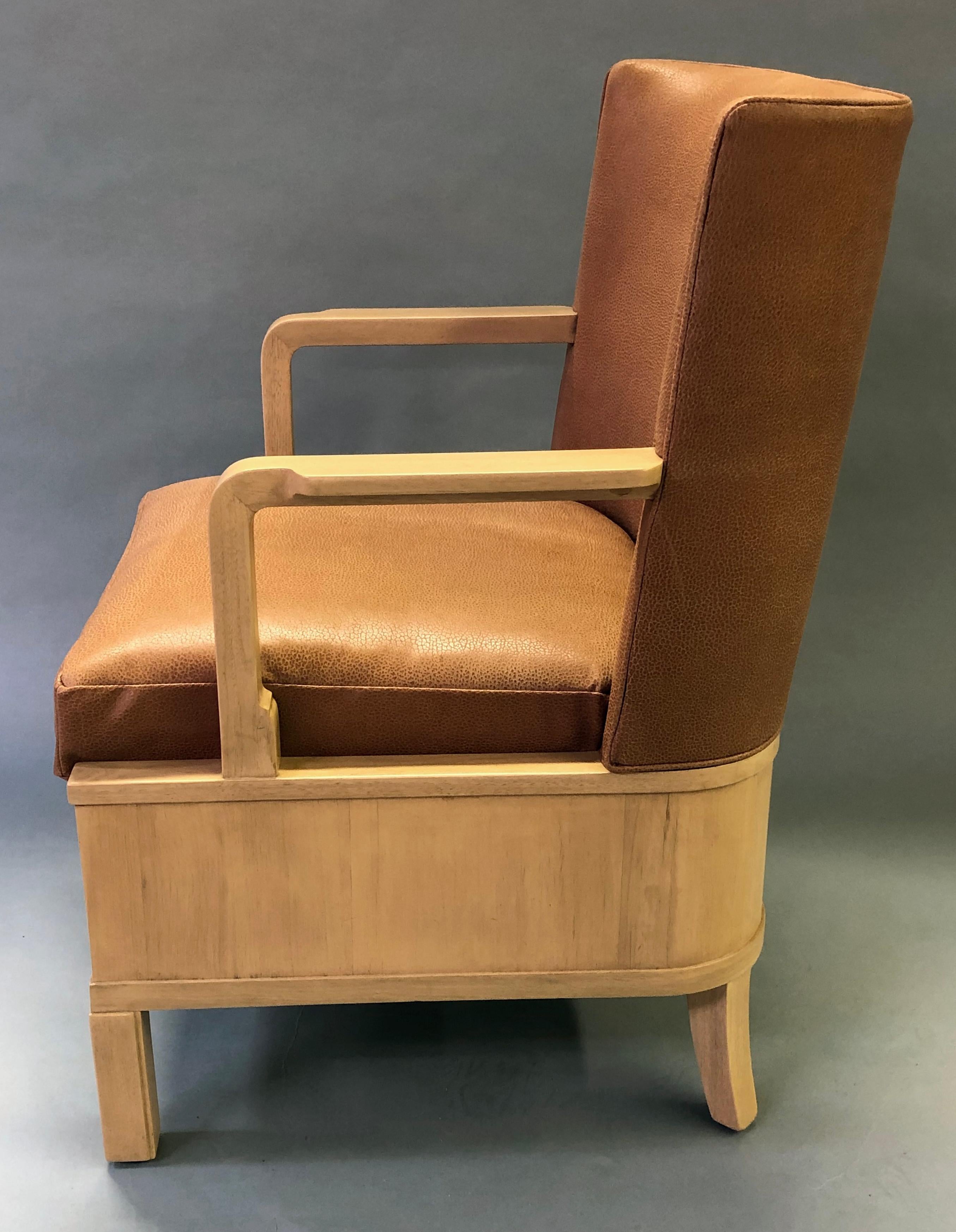 Each stylish and well designed chair with incurved upholstered back above a loose cushion seat flanked by squared arms over a u-shaped frame with inlaid marquetry.
