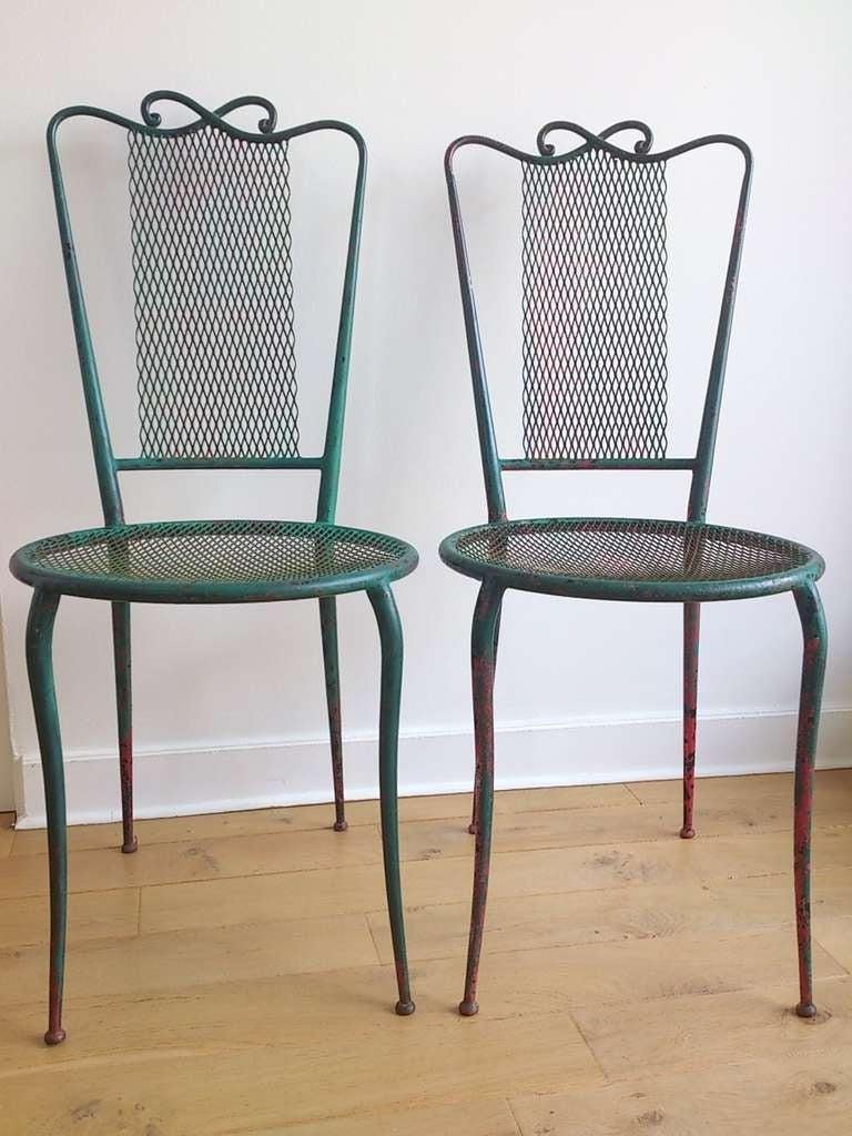 Pair of wrought 1950s iron chairs in the style of René Prou. Beautiful patina in green and red paint. Painted iron and rigitulle. Item is currently located in Paris, France.
