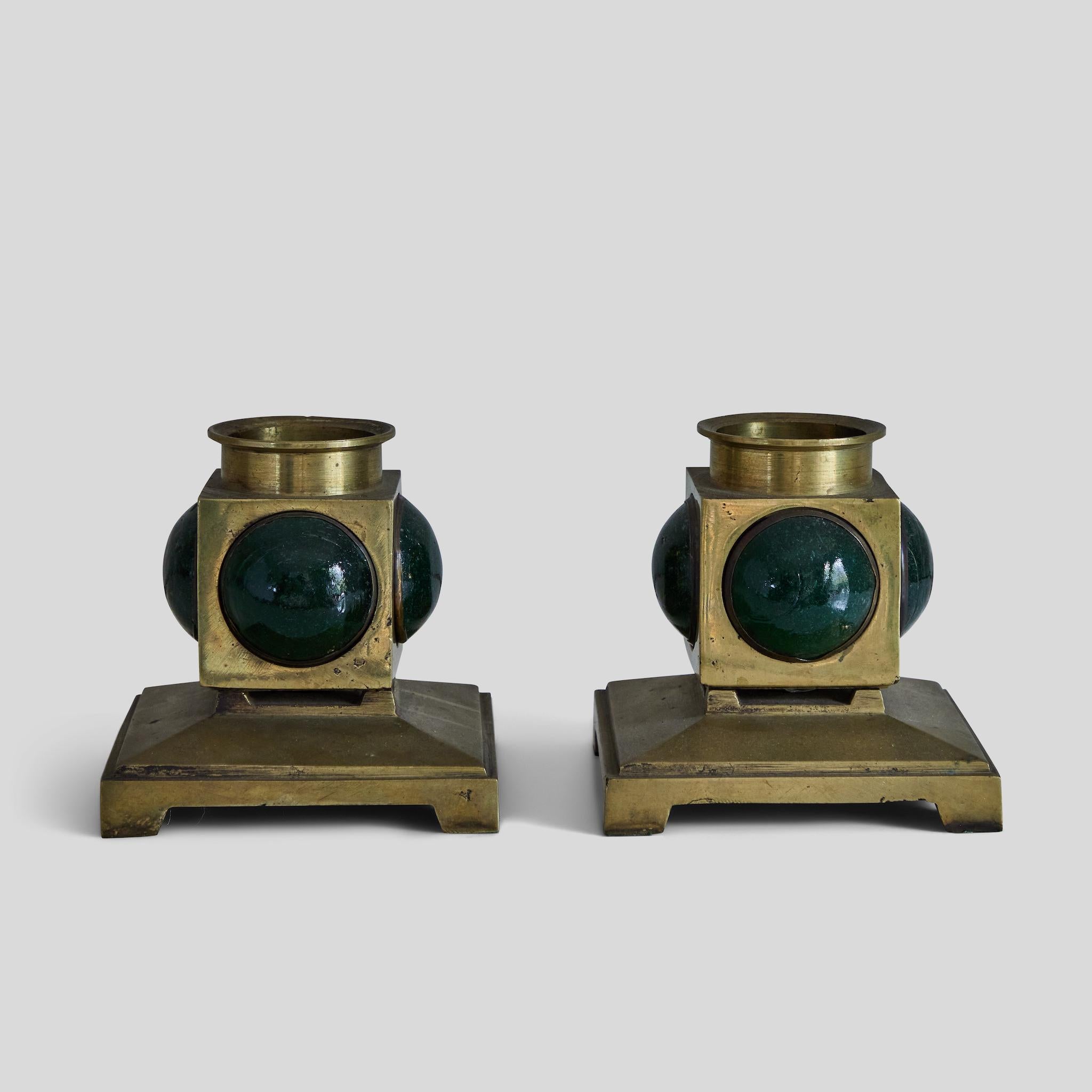 This is a pair of brass candlesticks dating from 1950s France with curved colored glass elements on each side. 