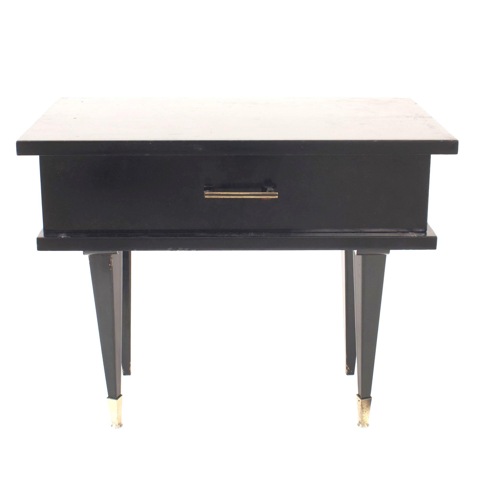 Pair of French mid-century (1950s) ebonized low bedside or end tables with a single drawer and tapered square legs having chrome sabot feet.
 