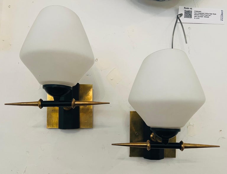 A wonderful pair of 1960s French sconces composed of brass horned and black enamel fixtures with white glass shades. Rewired