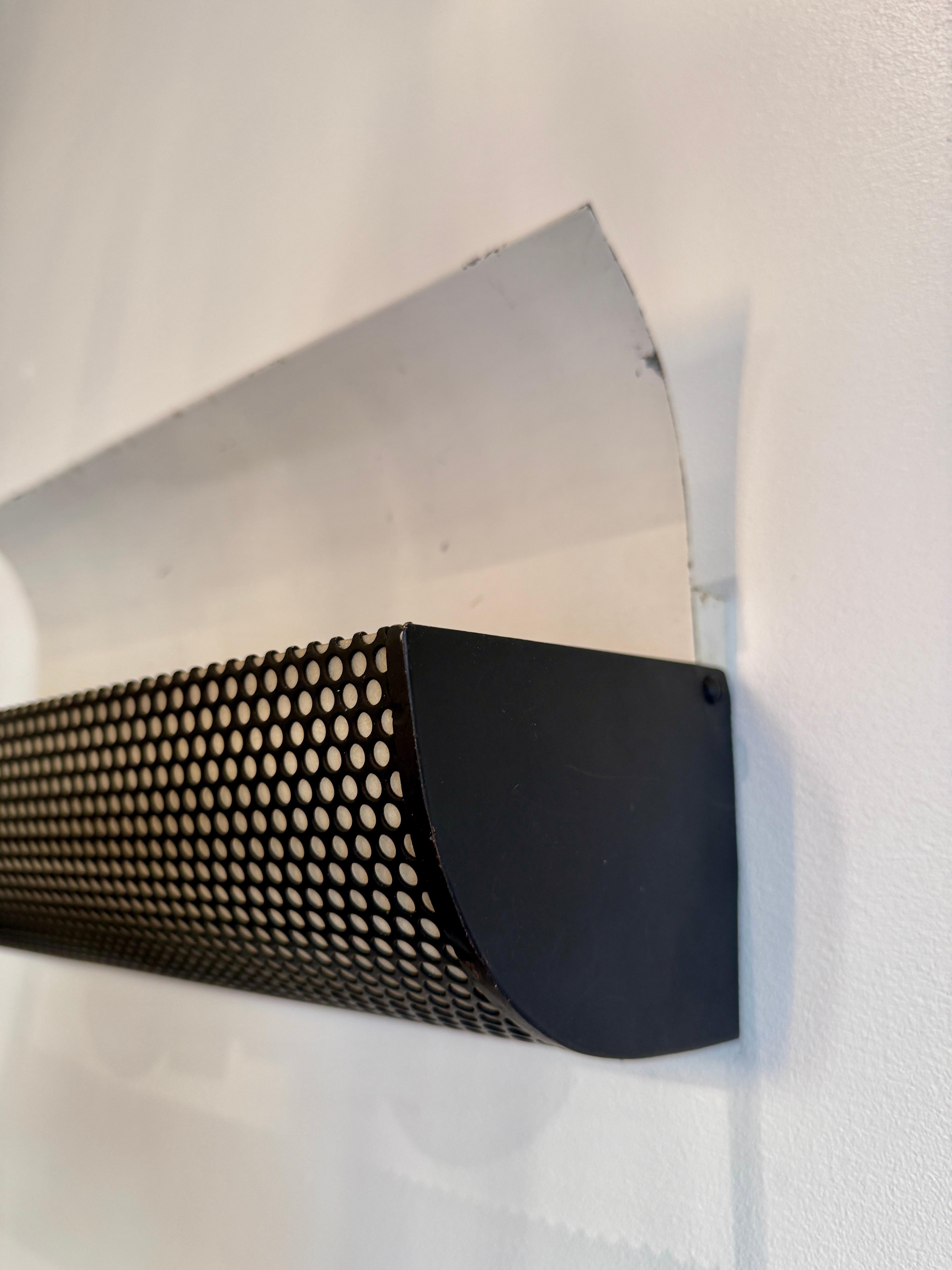 Este par de apliques de pared, al estilo de Matthieu Mategot, presentan un frontal de metal de malla pintado de negro y un interior blanco roto.  Recableado con casquillos nuevos, bombillas dobles por luz.  Un difusor superior abierto permite que la